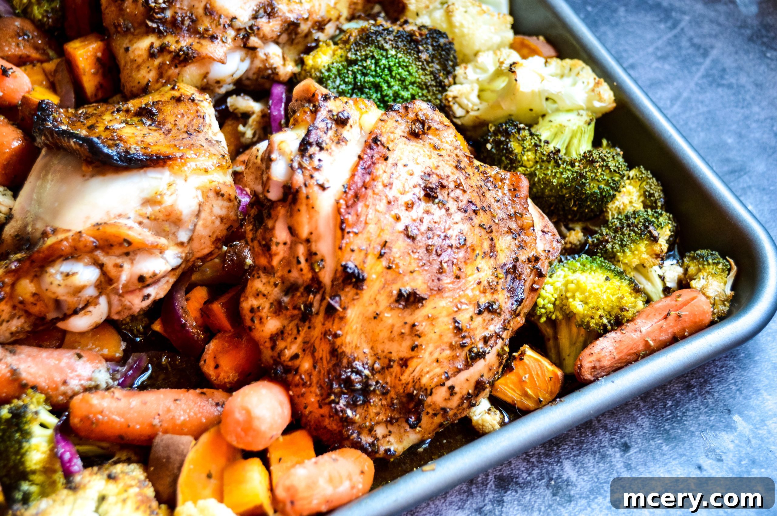 The complete sheet pan dinner, including chicken and vegetables, served on plates and ready to eat.