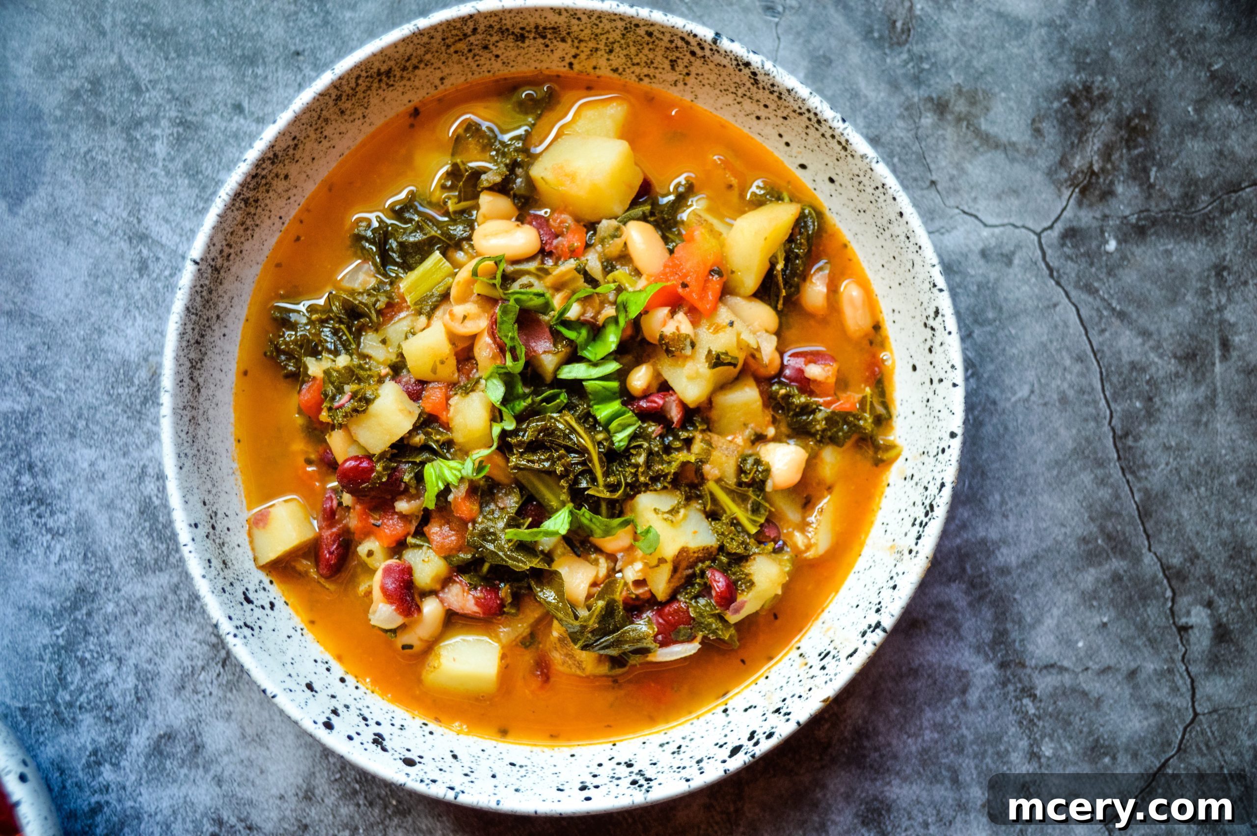 Hearty Instant Pot Vegan Bean Potato Kale Soup 3 Close-up of Instant Pot Bean Potato & Kale Vegan Soup with fresh basil garnish, showing rich texture and vibrant ingredients.