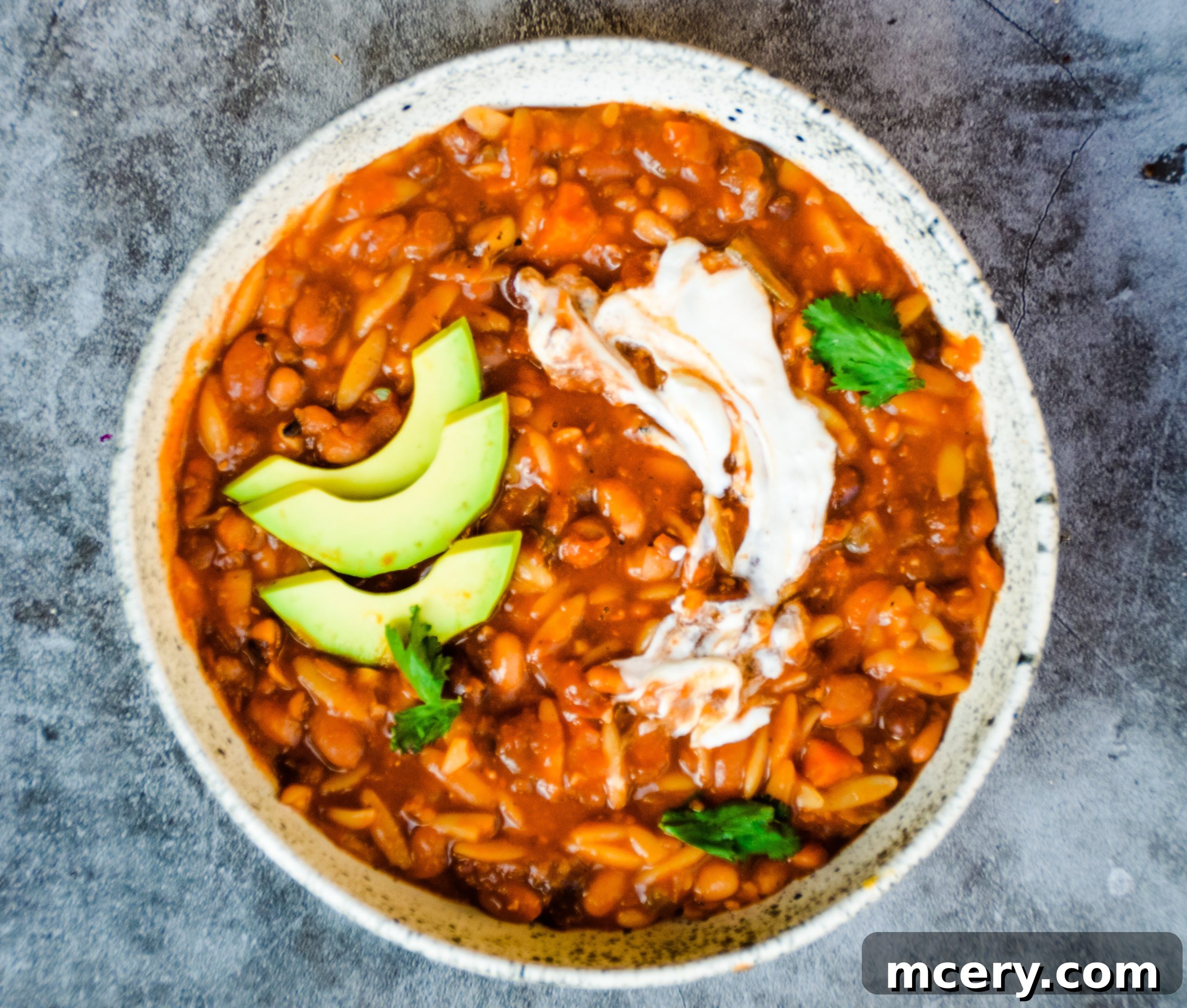 A vibrant bowl of Instant Pot Vegan 10 Bean Taco Soup, brimming with various colorful beans, vegetables, and a rich broth, garnished with fresh cilantro and a dollop of vegan sour cream. A cozy and inviting dish for a healthy meal.