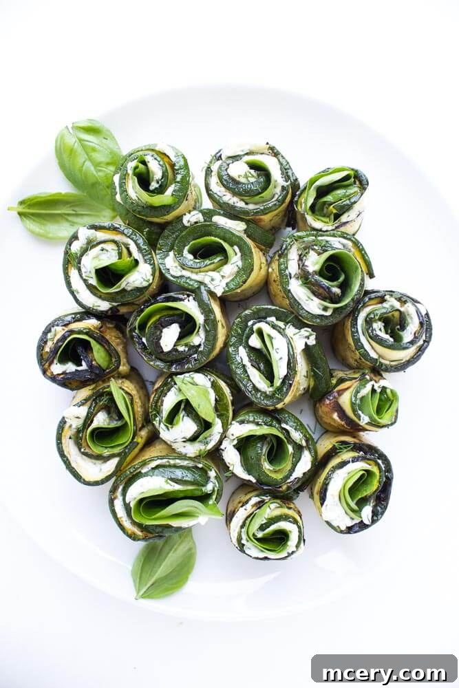 Creamy Zucchini Pinwheels 2 Grilled zucchini roll-ups, elegantly arranged on a platter, revealing a creamy herb cheese, baby spinach, and fresh basil filling. Perfect for healthy entertaining.