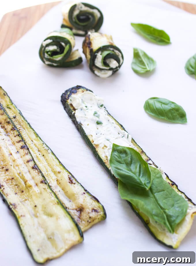 Creamy Zucchini Pinwheels 3 Close-up of a single grilled zucchini roll-up, showcasing its vibrant green hue and the rich, creamy herb cheese filling with fresh spinach and basil.