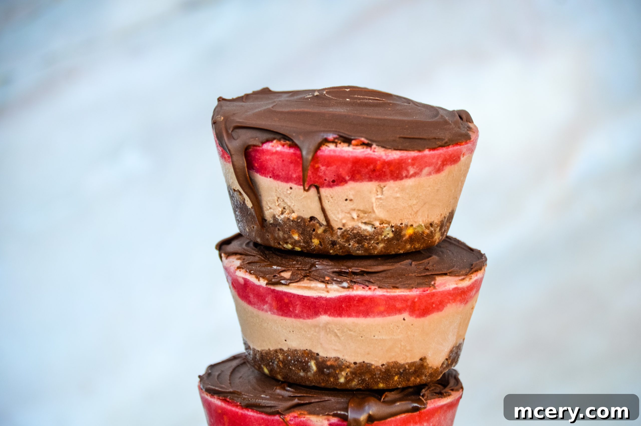 Assortment of fresh ingredients for vegan chocolate raspberry cakes, including nuts, dates, and fresh berries, on a wooden board
