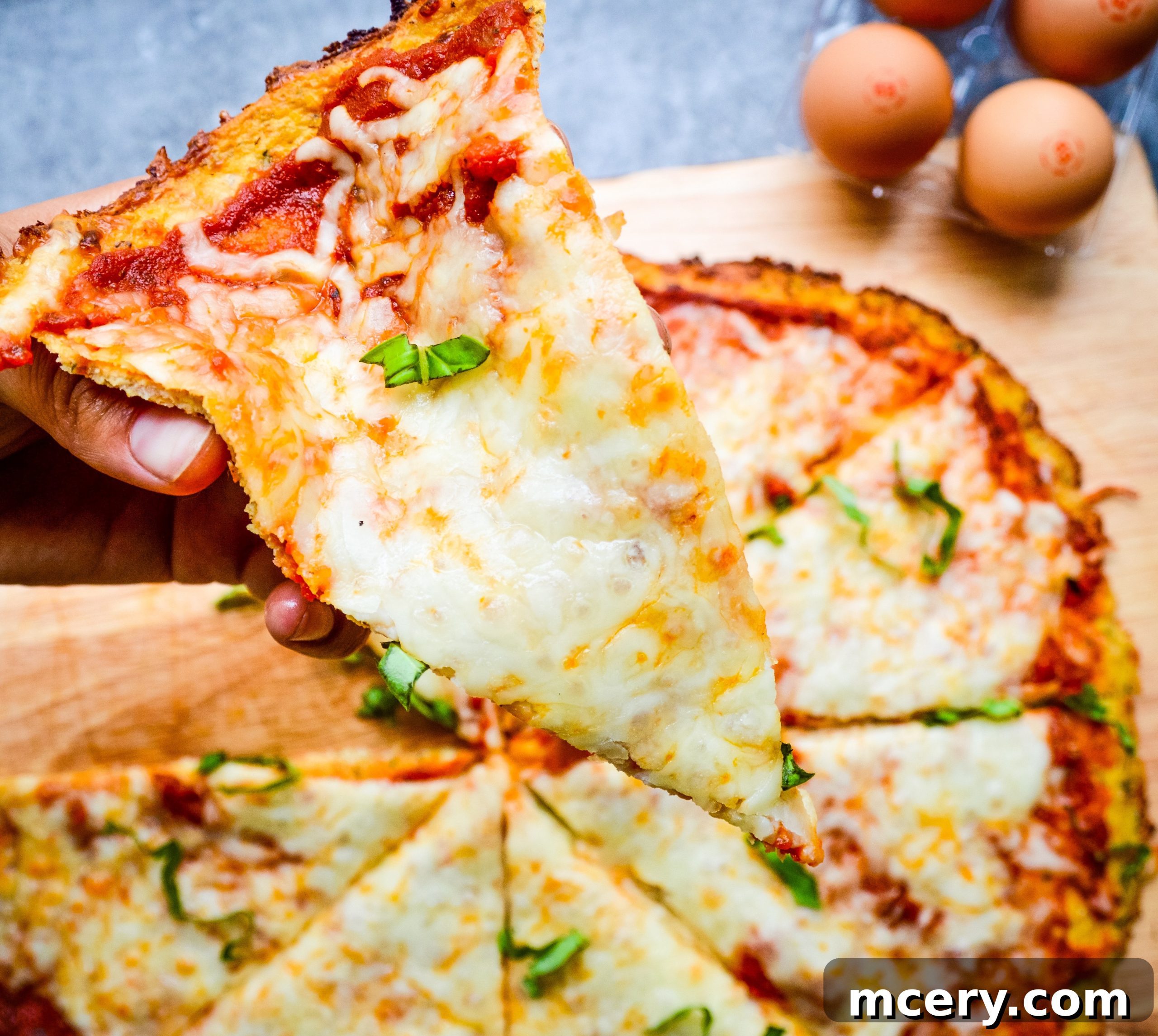 The Ultimate Cauliflower Pizza Base 2 A perfectly baked cauliflower pizza crust topped with melted cheese and fresh herbs, ready for toppings.