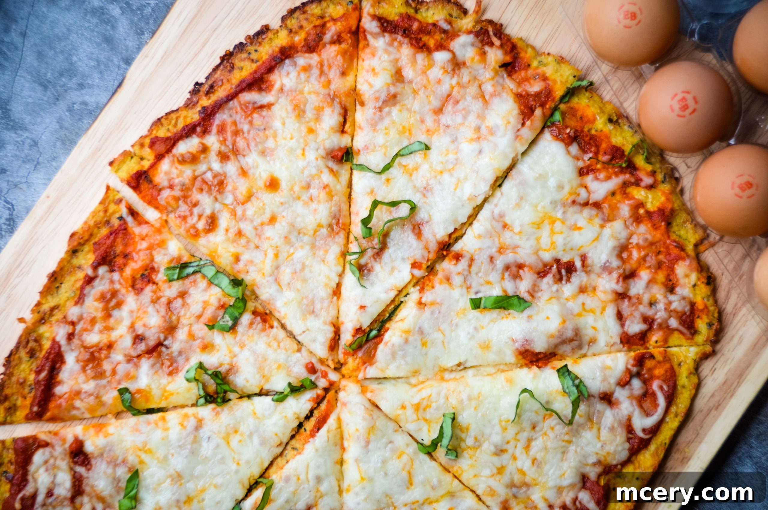 The Ultimate Cauliflower Pizza Base 4 Ingredients for cauliflower pizza crust laid out: cauliflower florets, eggs, and shredded cheese.