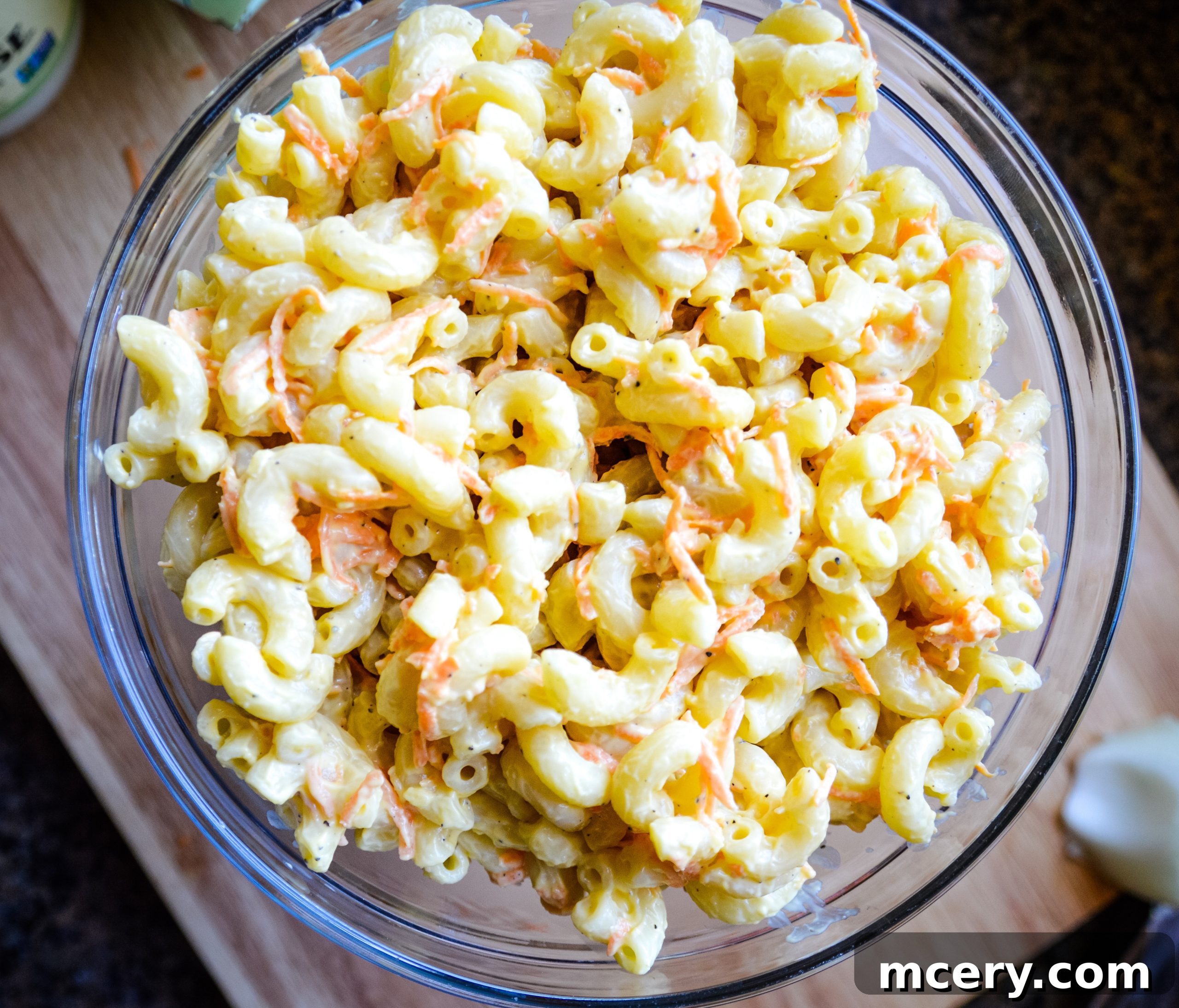 Guilt-Free Hawaiian Macaroni Salad 4 A freshly made bowl of Healthier Hawaiian Macaroni Salad, ready to be served, sitting on a dark wooden surface.