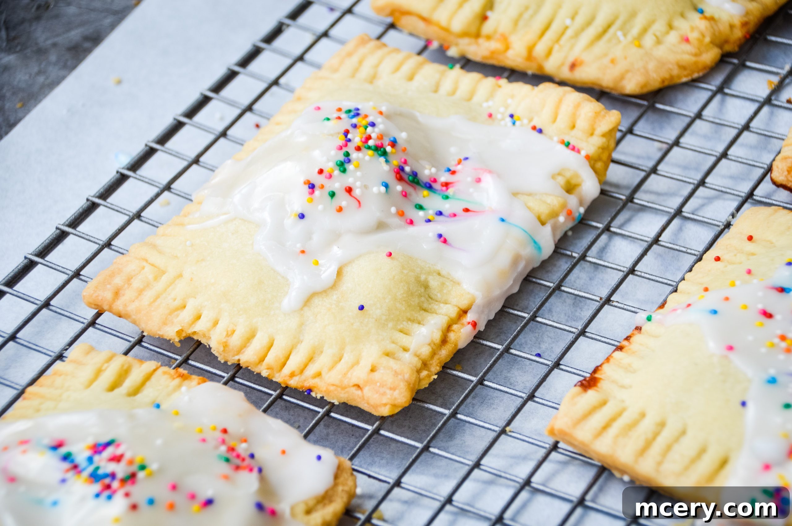 Sweet Strawberry Toaster Treat 2 Freshly baked homemade strawberry pop-tarts cooling on a rack, with a golden-brown crust and white icing.