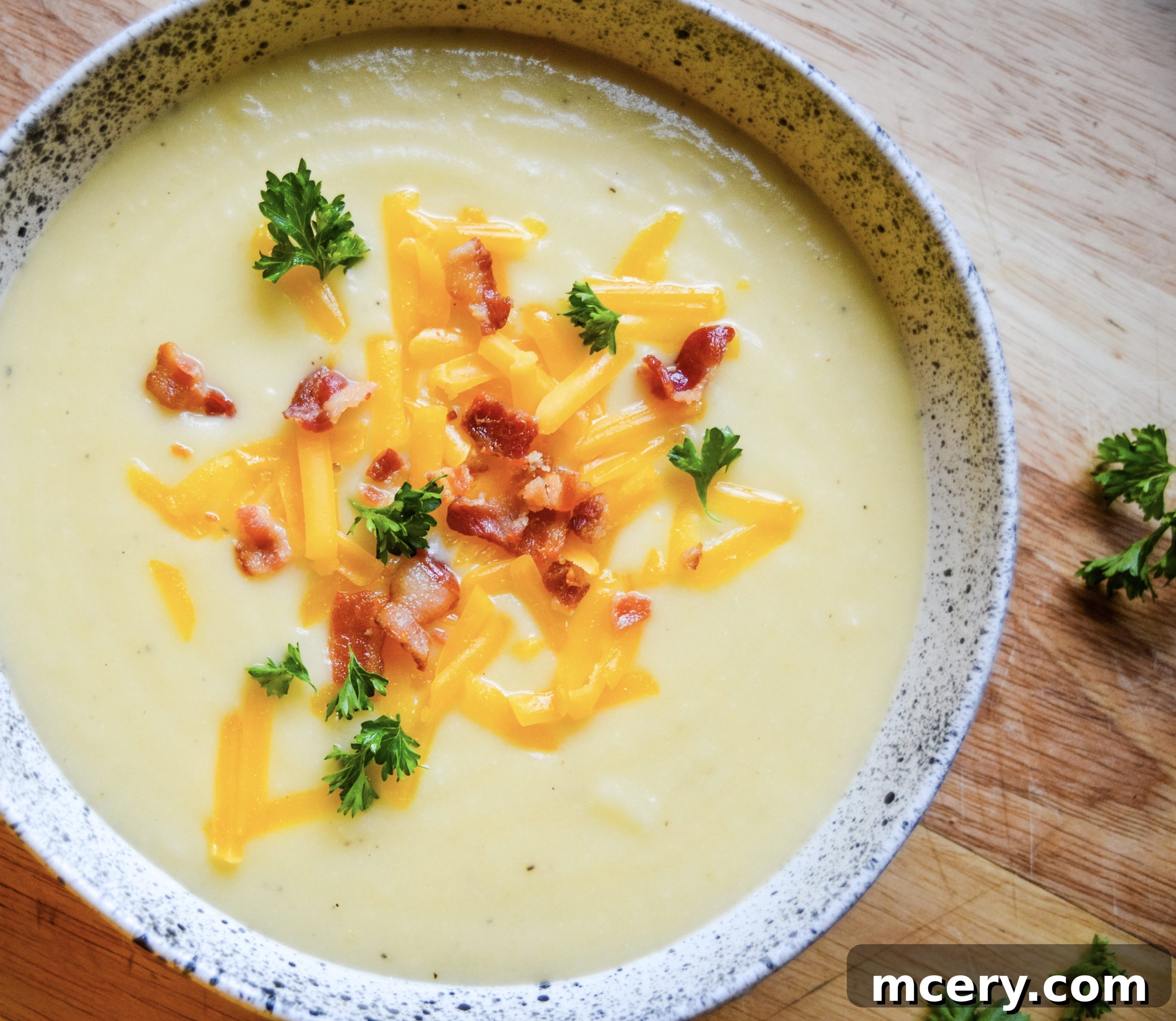 Instant Pot Velvety Cauliflower Cheese Soup 5 A beautifully composed flat lay of the creamy cauliflower cheese soup, garnished with vibrant green herbs and crispy bacon bits, ready to be enjoyed.