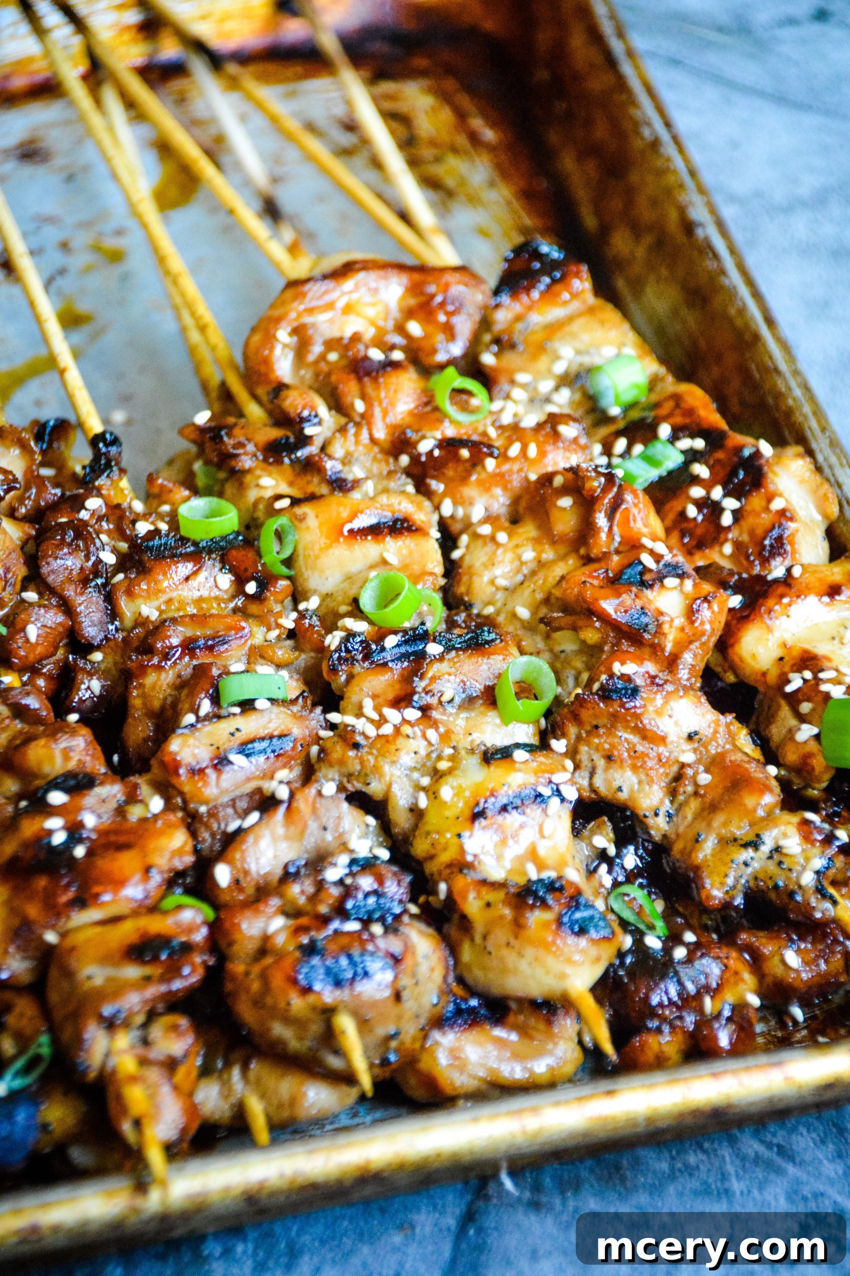 Sticky Teriyaki Chicken Skewers 4 A close-up of Teriyaki Chicken Skewers sizzling on a cast iron pan, showing the charring and glossy glaze.