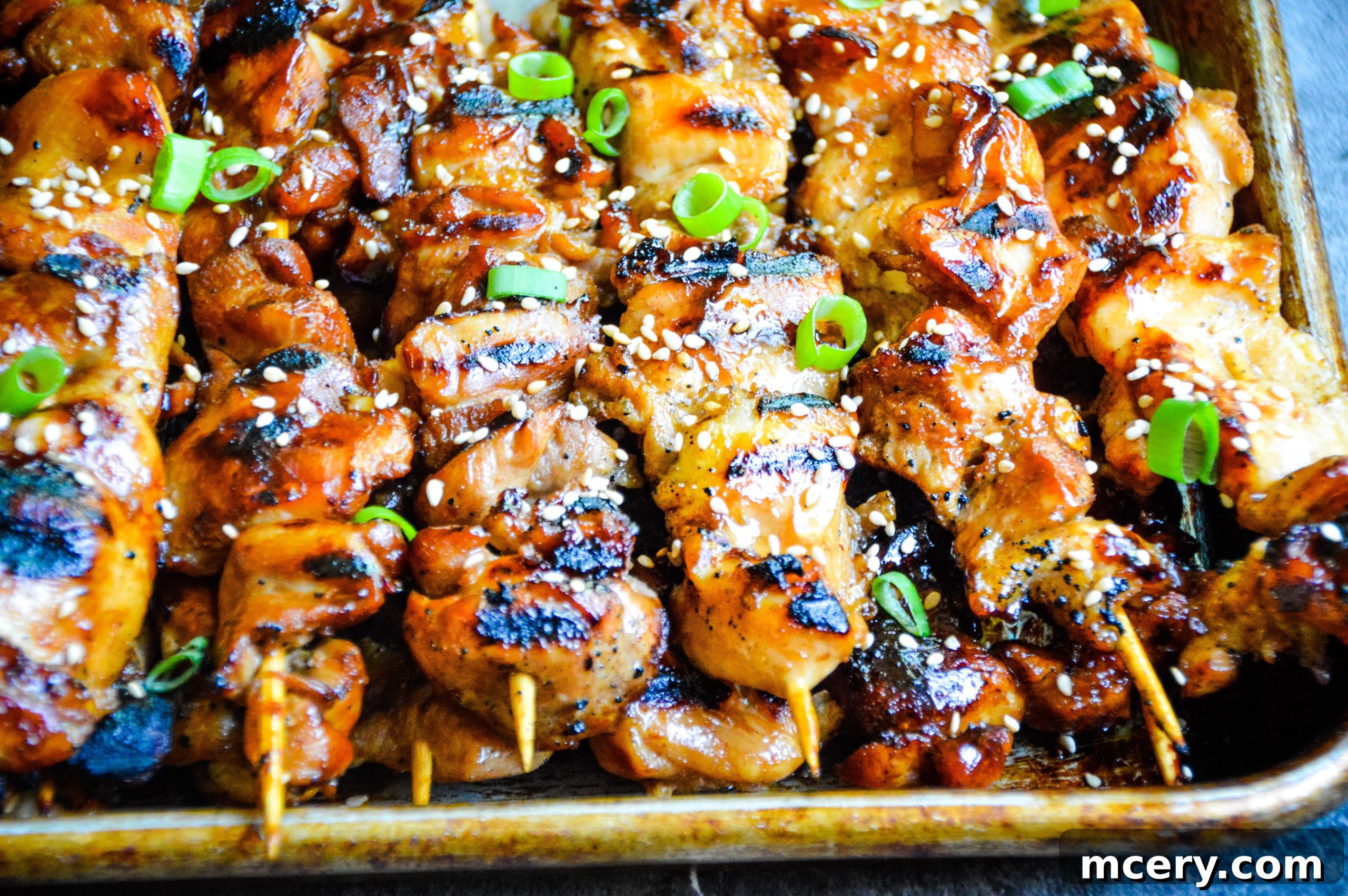 Sticky Teriyaki Chicken Skewers 7 Plated Teriyaki Chicken Skewers, garnished with green onions and sesame seeds, ready to be served.