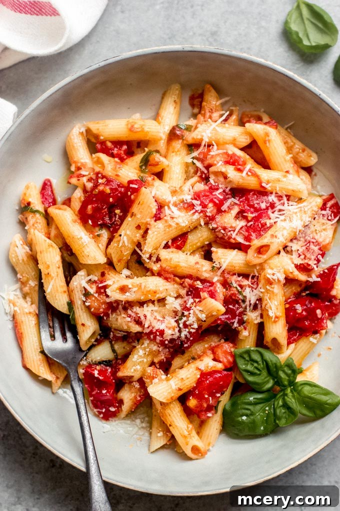 Pasta Margherita 2 A vibrant bowl of Margherita Pasta, showcasing fresh penne, bright red tomatoes, green basil leaves, and grated Parmesan cheese, ready to be enjoyed.