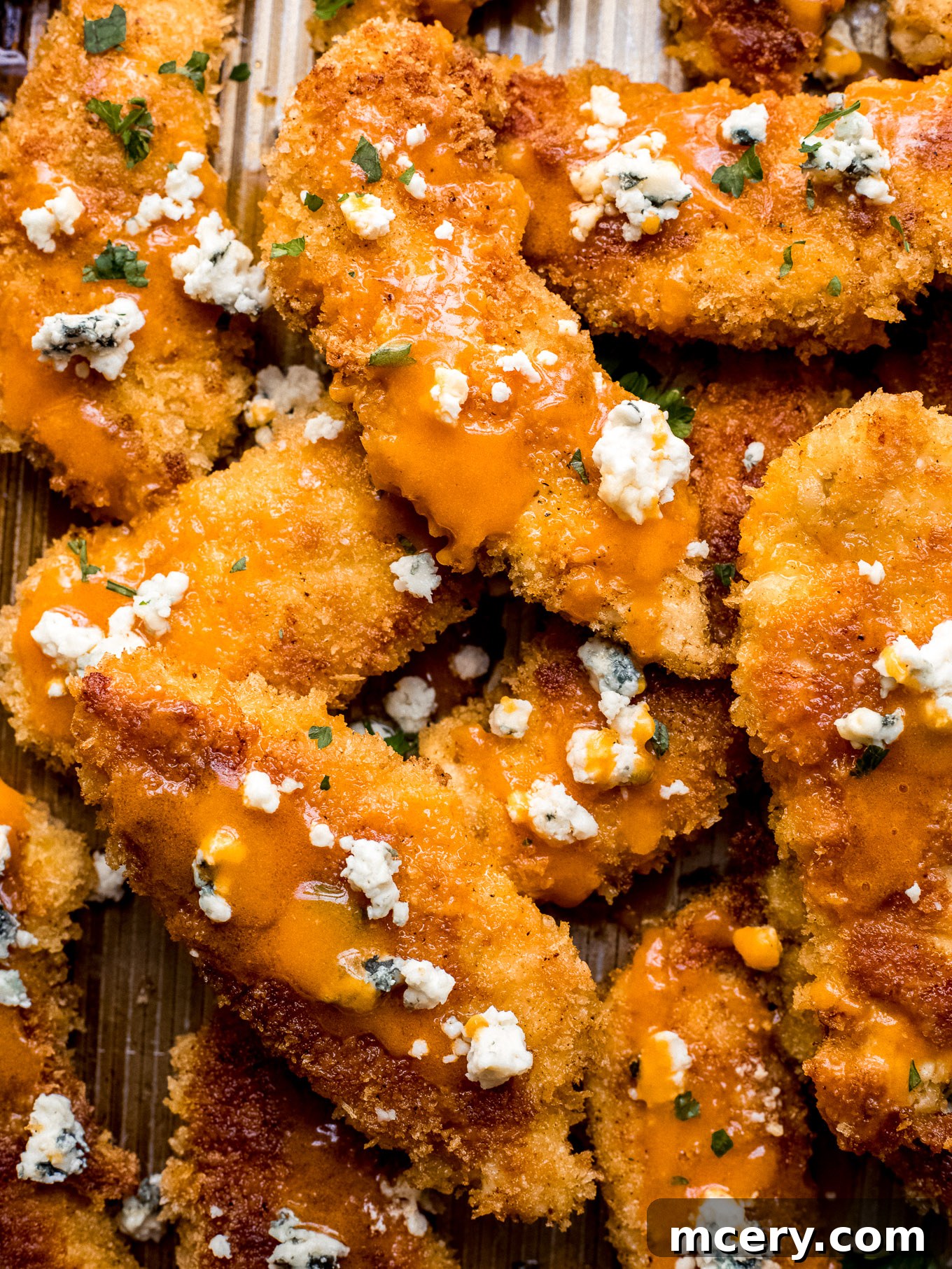 Close-up of baked buffalo chicken tenders with sauce and cheese, ready to serve.