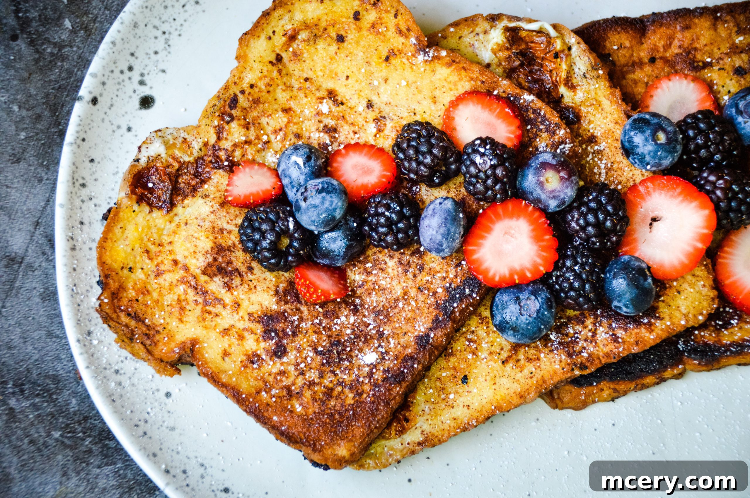 Golden brown French Toast slices topped with fresh berries and powdered sugar, ready for a delightful brunch.