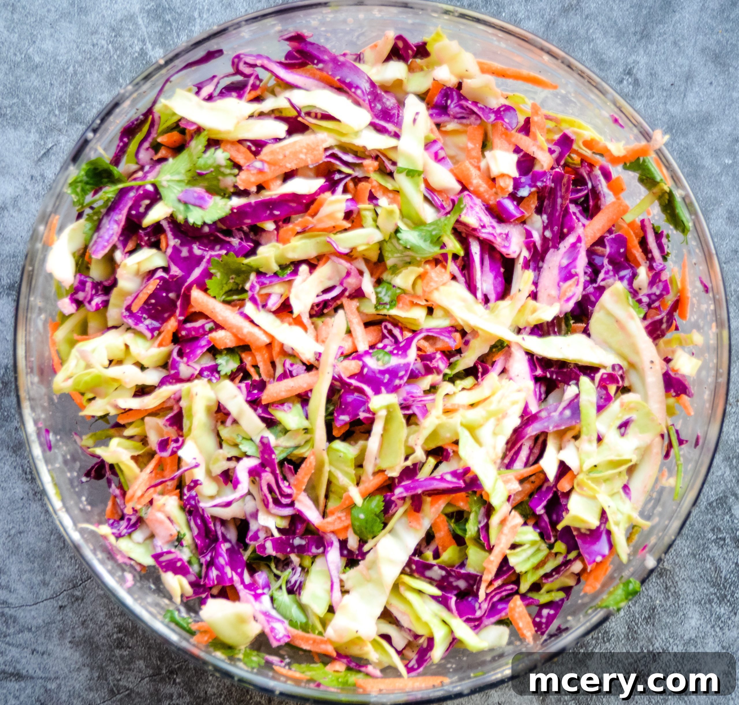 Glazed Asian Steak Bites with Zesty Slaw Bowl 5 A vibrant bowl of fresh coleslaw, showing shredded green and purple cabbage, carrots, and cilantro, ready to be dressed.