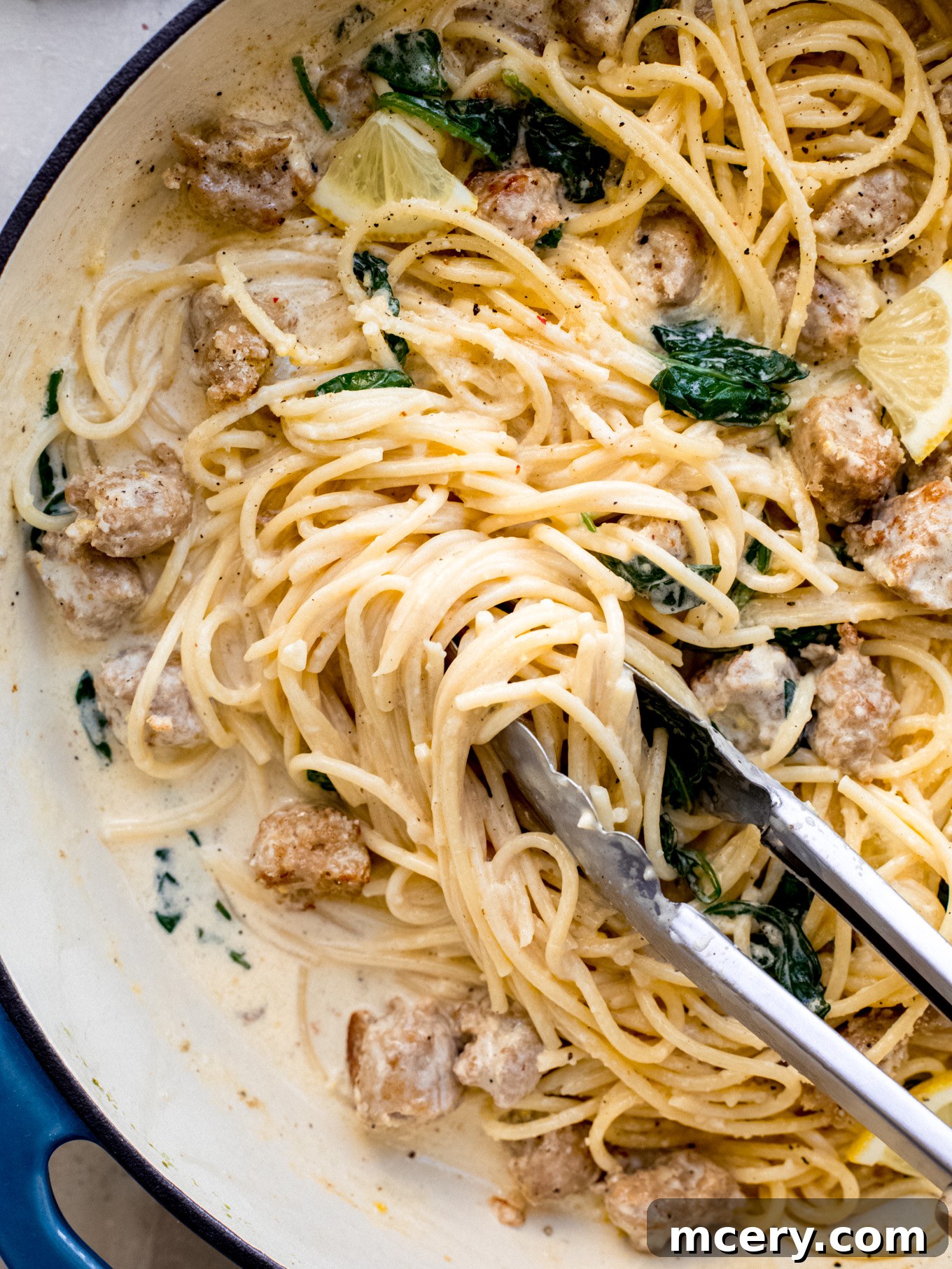 Bright Lemon Sausage Pasta 3 Lemon pasta with Italian sausage and wilted spinach in a large pan