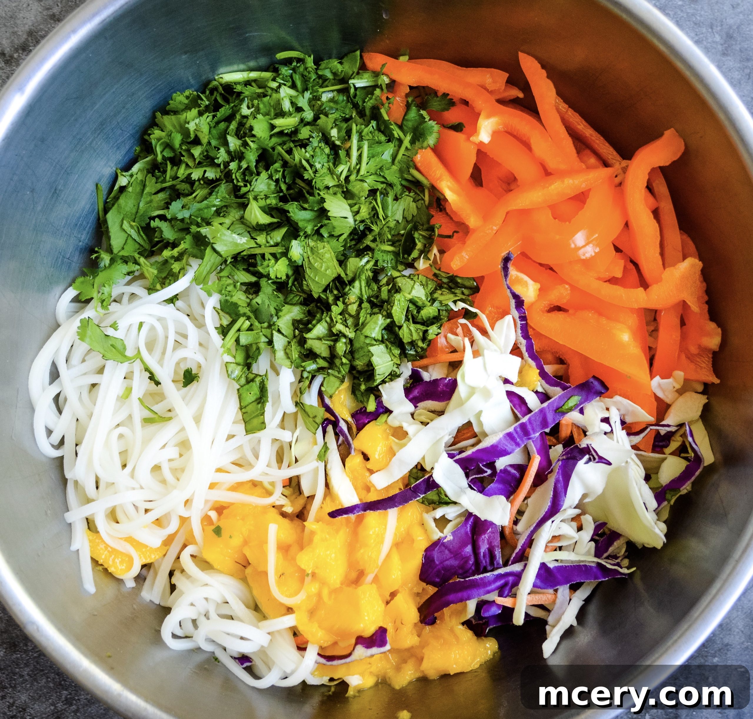 Fresh Vegetables & Herbs for Thai Noodle Salad A vibrant display of fresh ingredients for Thai Noodle Salad, including chopped cabbage, shredded carrots, bell peppers, mint, basil, and cilantro, artfully arranged on a cutting board.