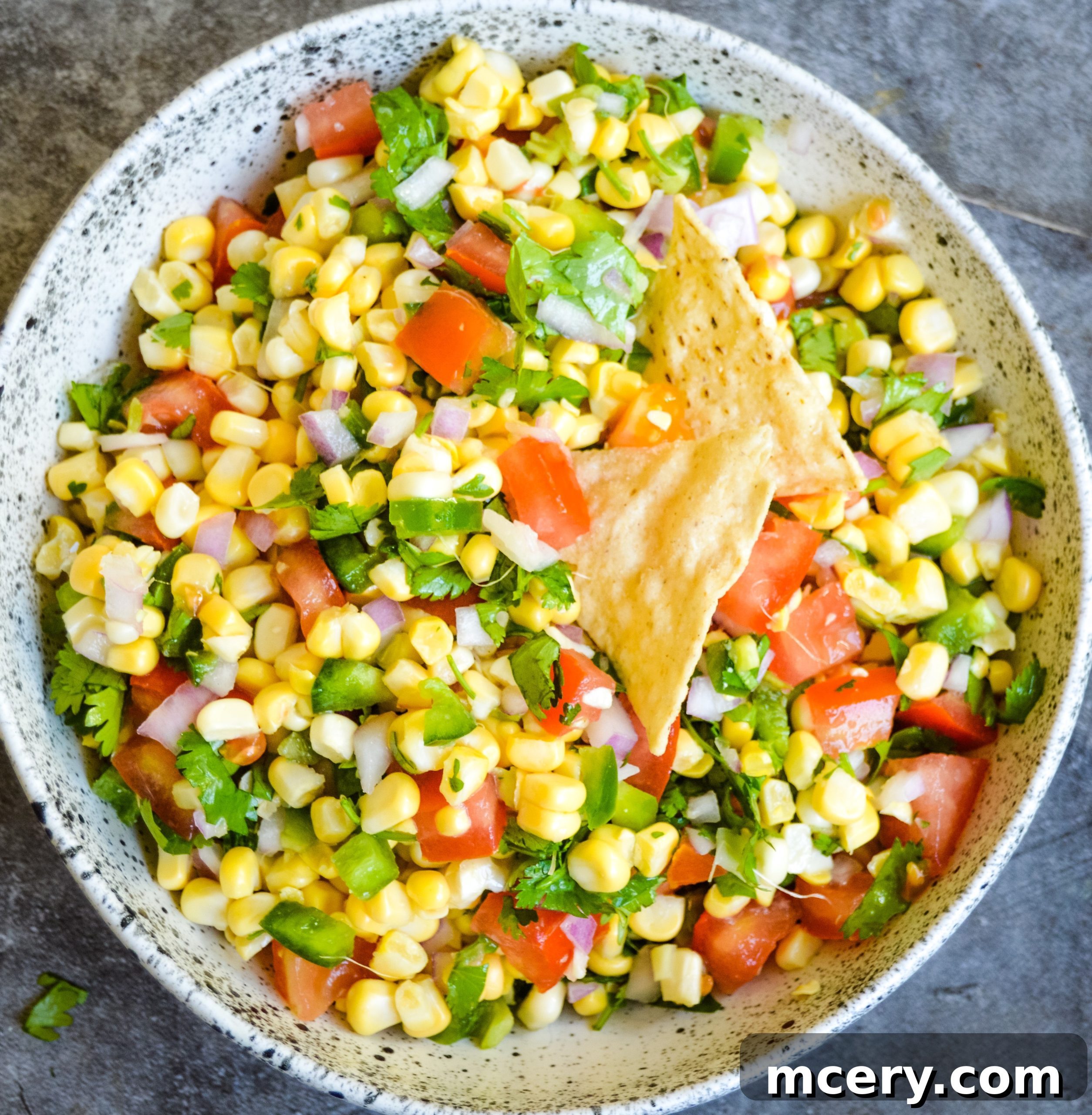 Sunshine Corn Salsa 2 A close-up shot of vibrant fresh corn salsa in a bowl, showing corn kernels, red onion, tomatoes, and cilantro.