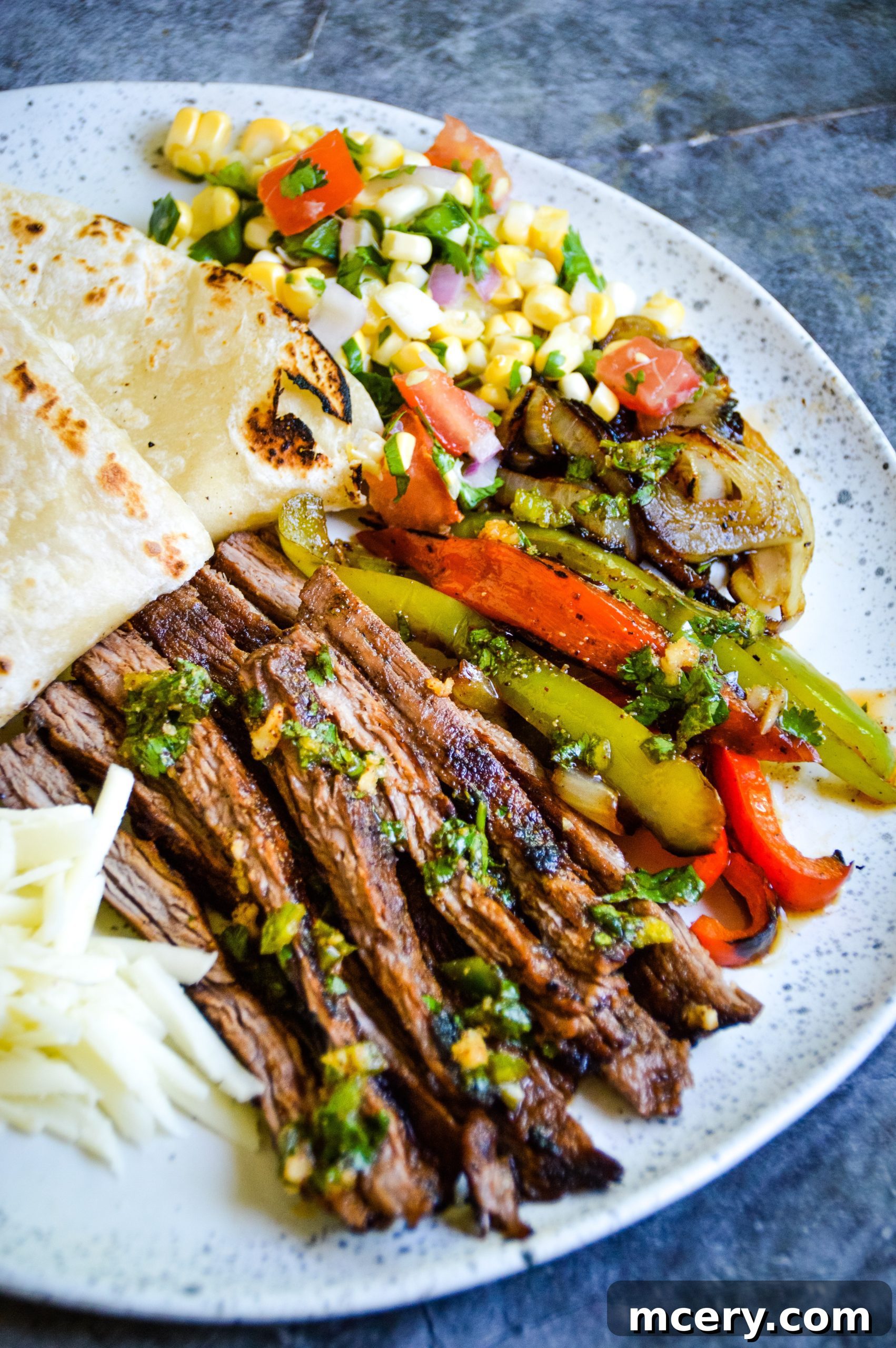 Marinated flank steak ready for grilling, alongside fresh vegetables.