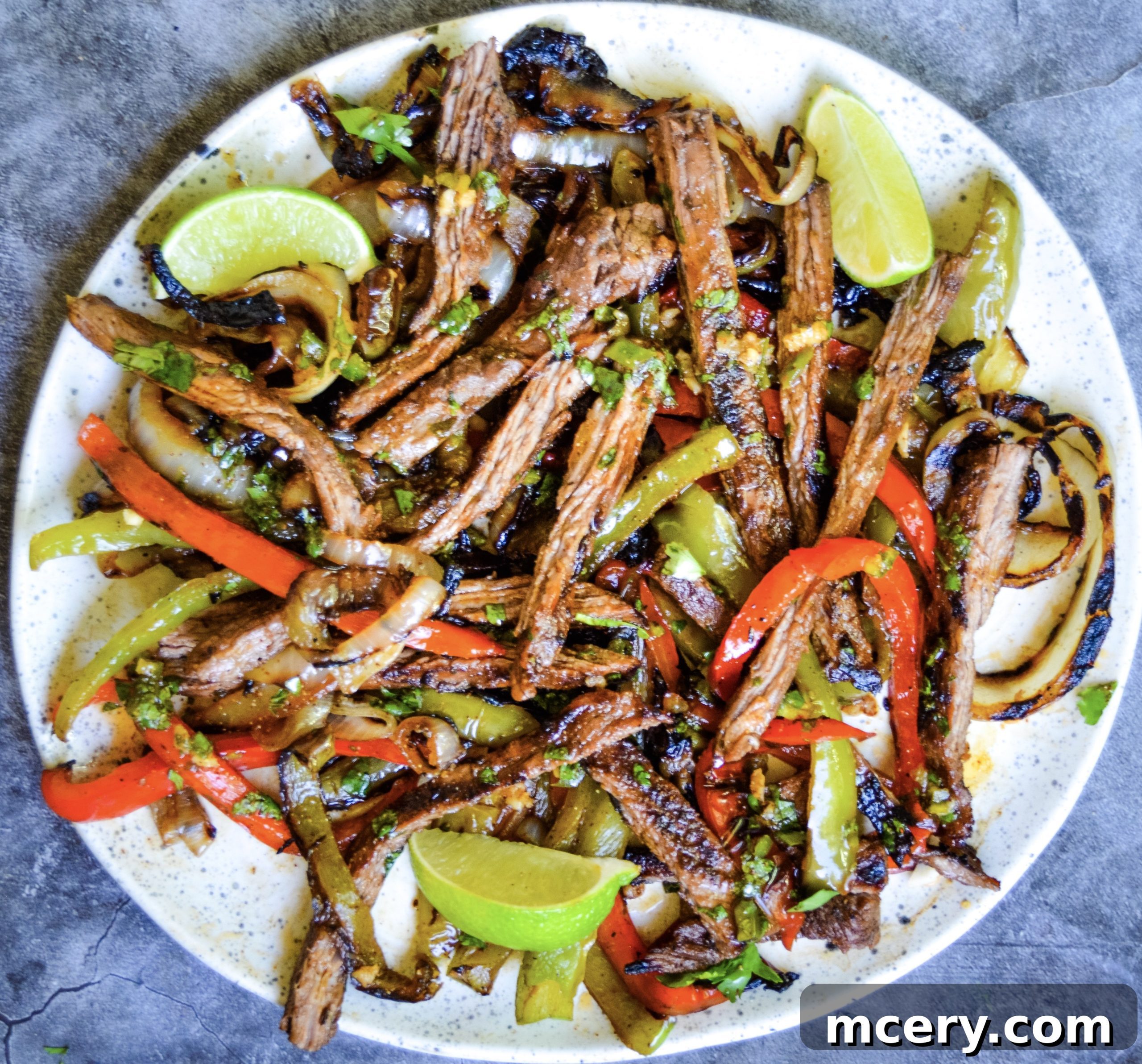 A large platter of cooked steak fajitas, ready to be served family-style.