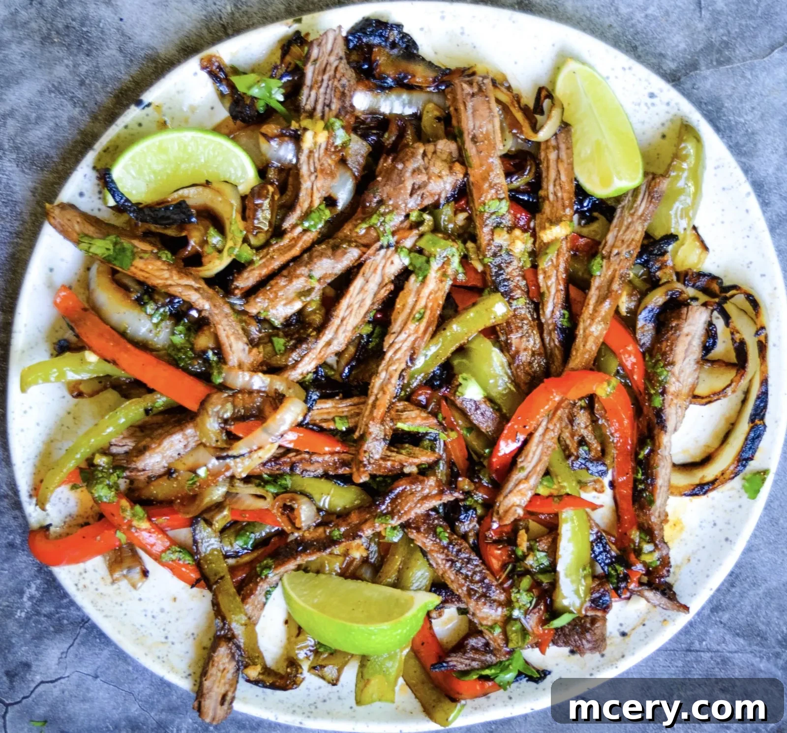 A close-up of a sizzling steak fajita platter, showcasing the charred ingredients.