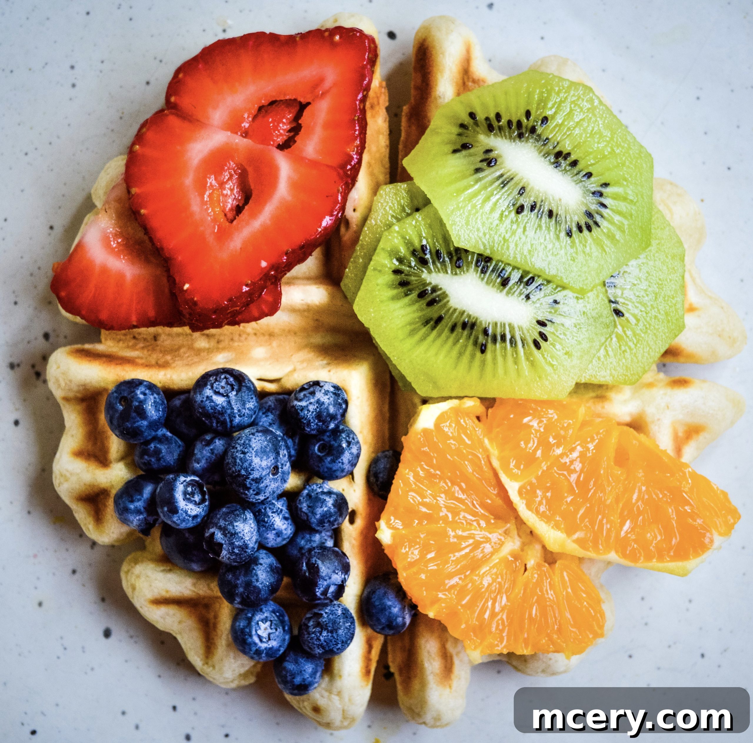 Hands pouring waffle batter into a preheated waffle maker.