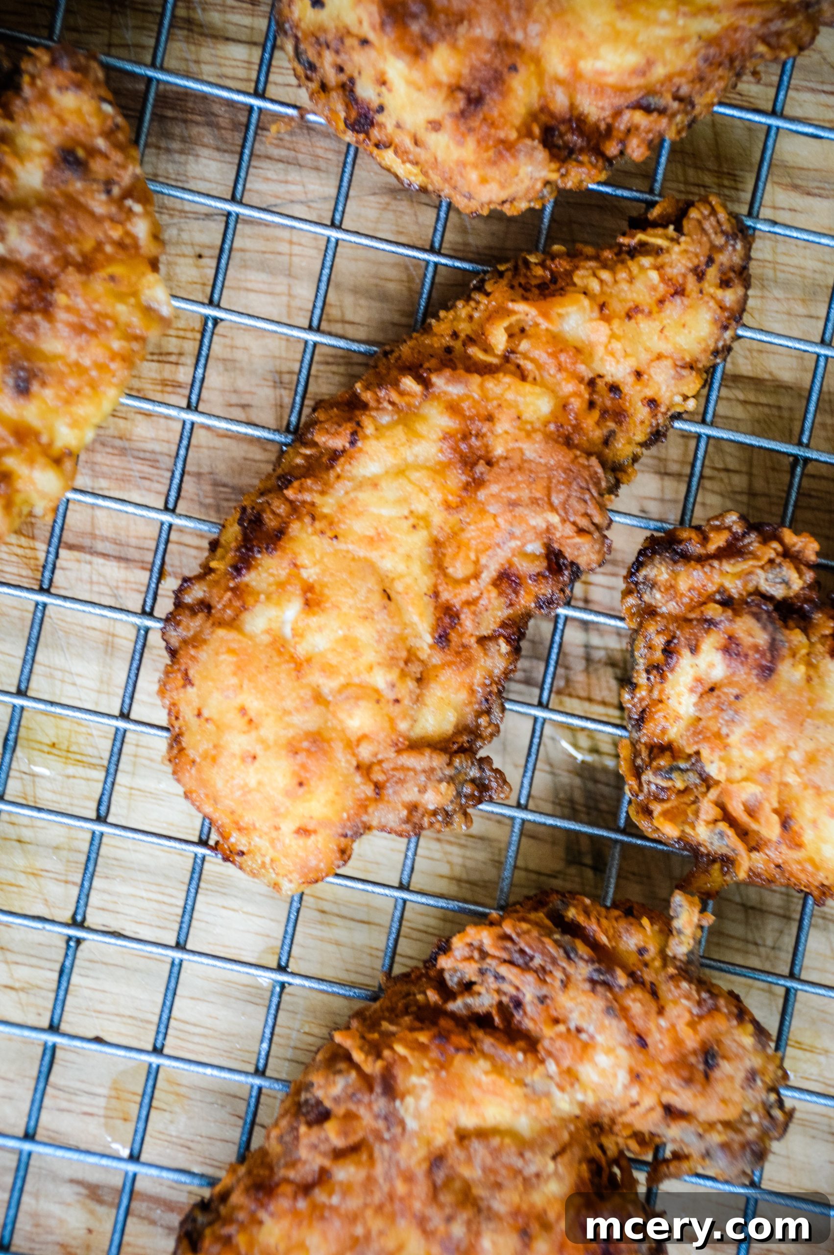 Golden Crunchy Chicken Strips 5 A freshly fried chicken tender being removed from the cast iron skillet.