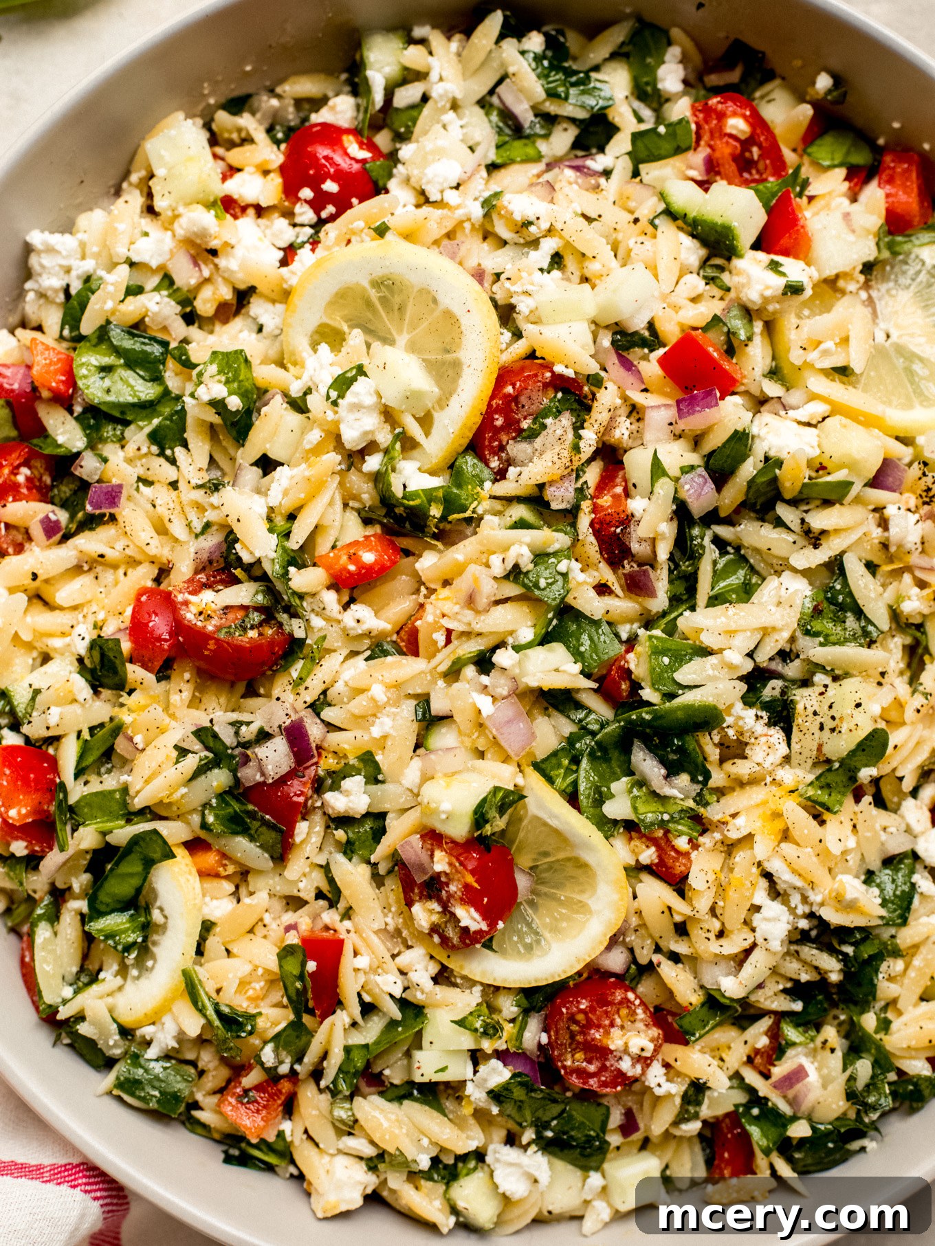 Bright Lemon Orzo Salad 7 Close-up view of lemon orzo pasta salad, highlighting crunchy vegetables and crumbled feta cheese.