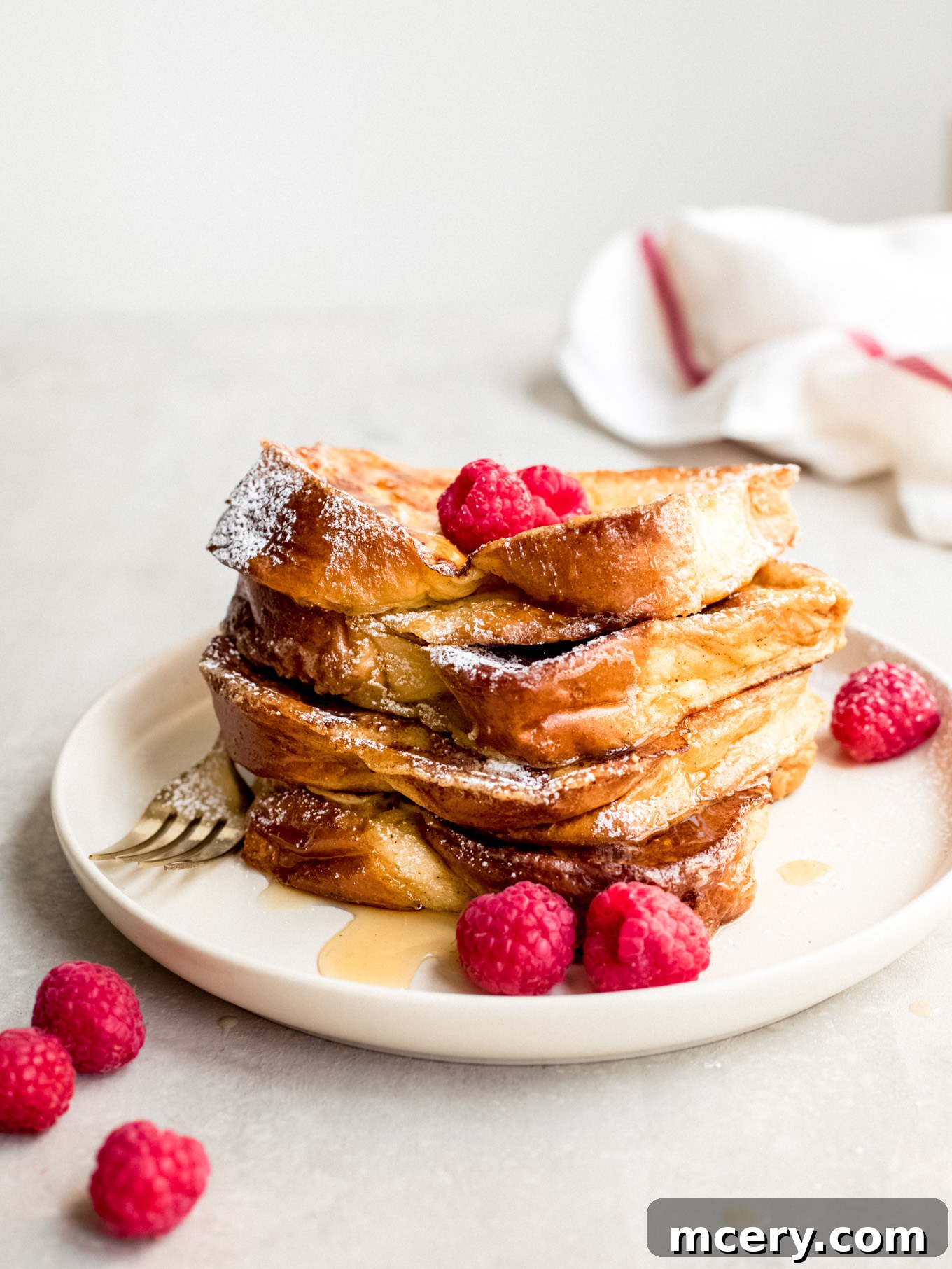 Golden Brioche French Toast Perfection 3 Stacked brioche French toast slices on a plate, garnished with berries and powdered sugar.