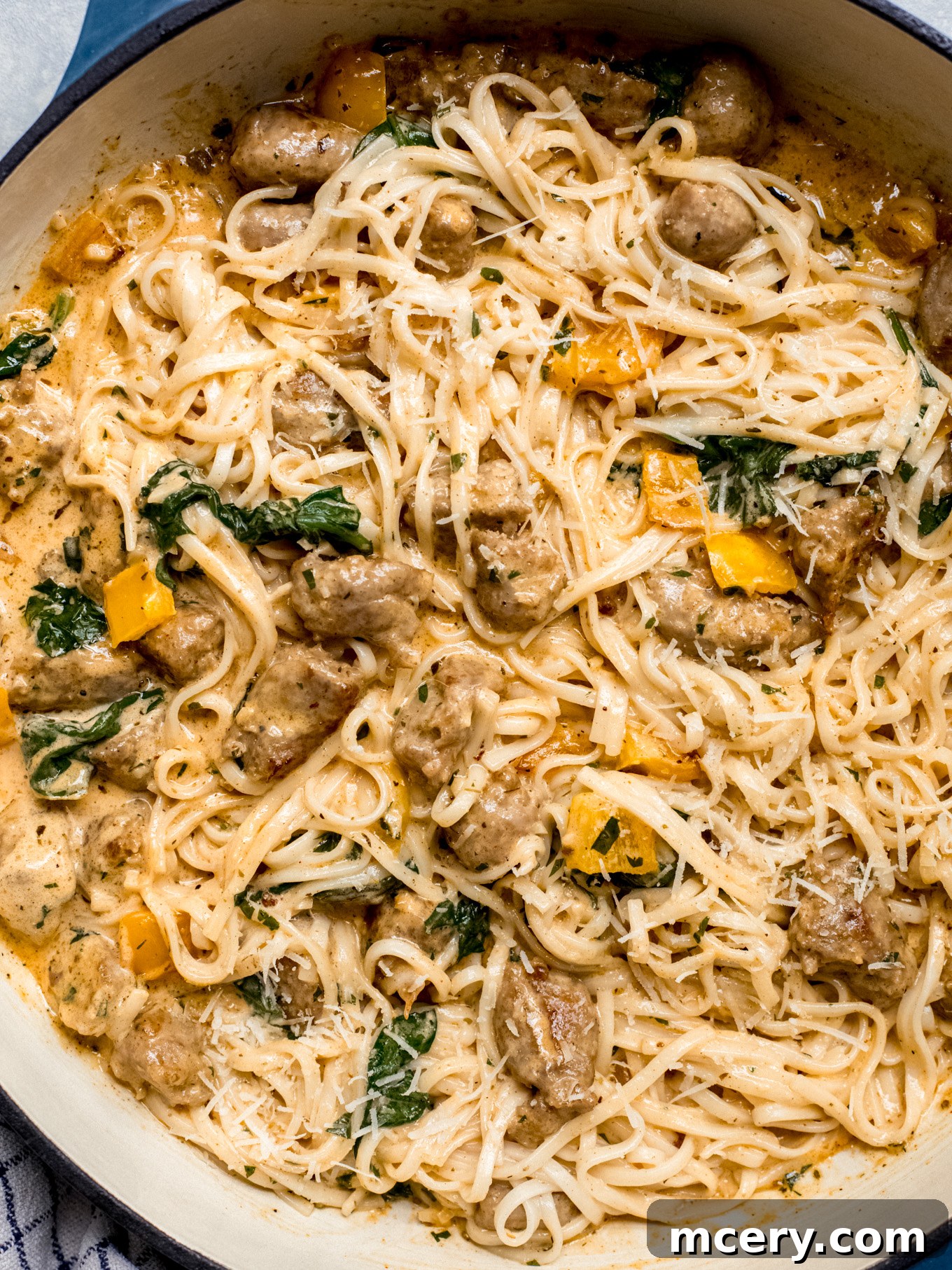 Irresistible Creamy Cajun Sausage Pasta 10 close up of creamy pasta with cream sausage, Italian sausage, bell peppers, and spinach in a skillet.