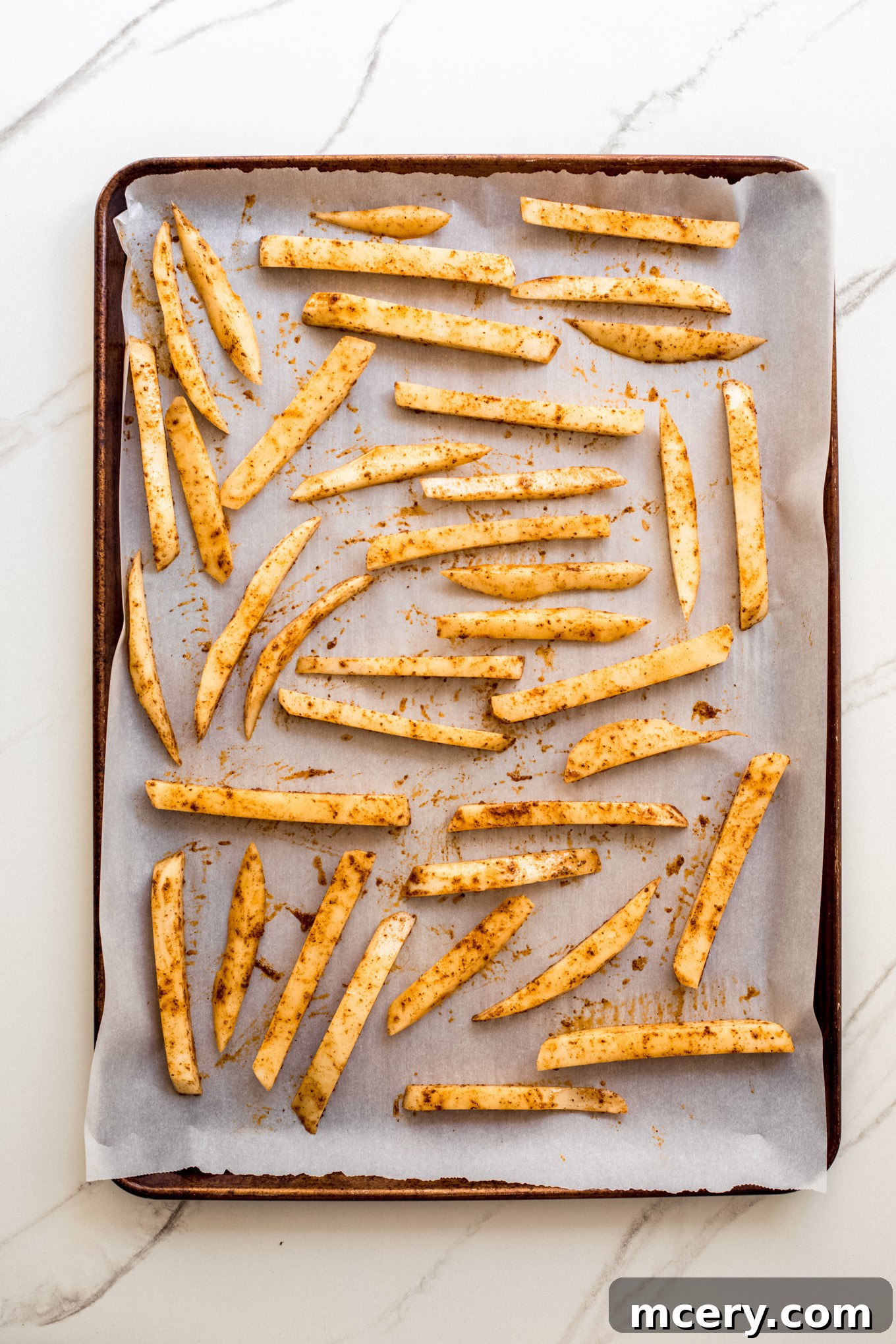 Signature Old Bay Fries 9 french fries on a baking sheet lined with parchment paper.
