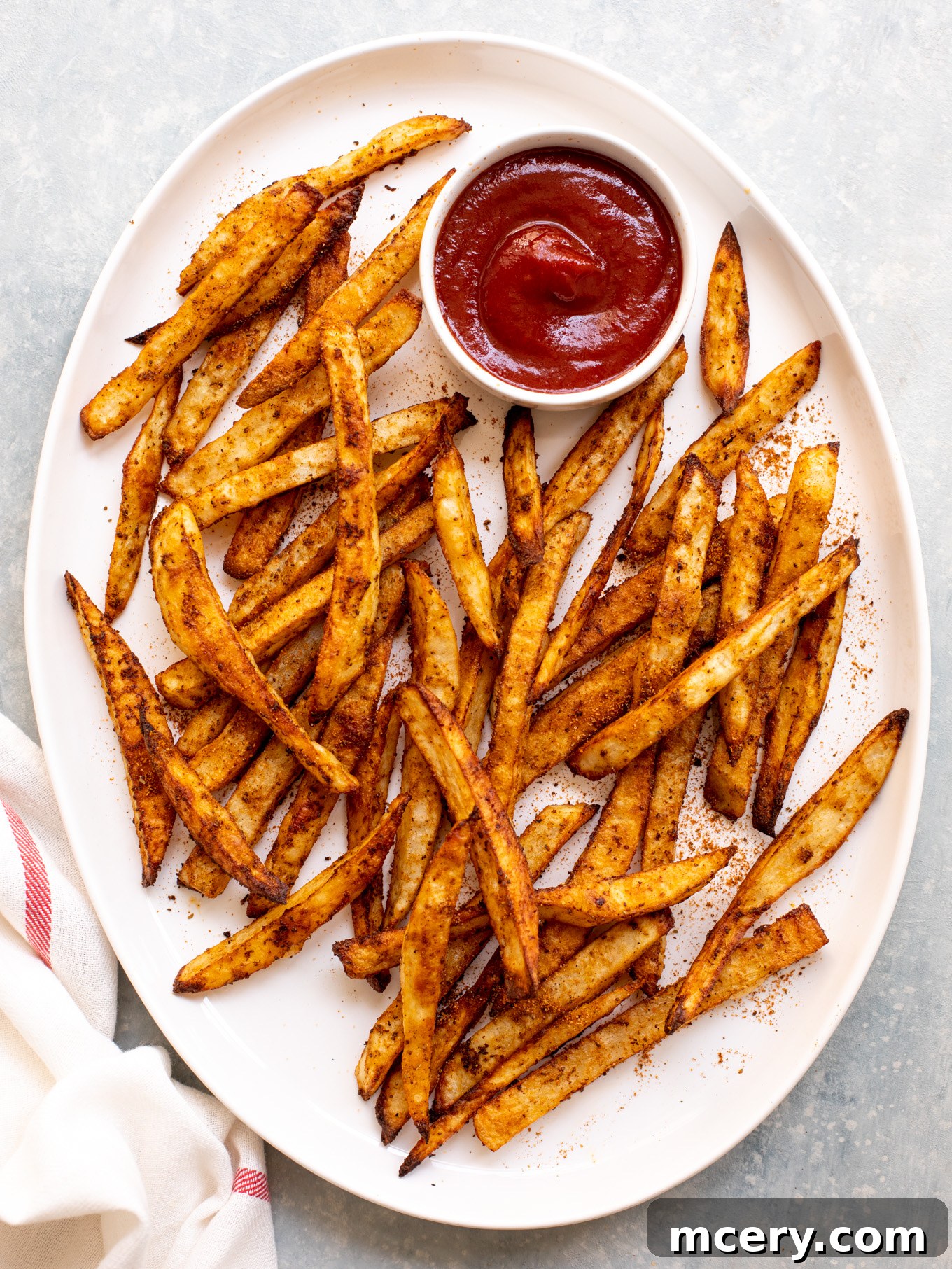 Signature Old Bay Fries 10 french fries on a white platter with a ketchup to the side.