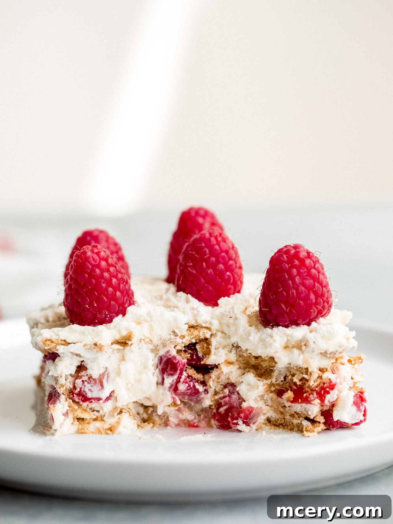 A delicious slice of no-bake icebox cake, showing distinct layers of softened graham crackers, fluffy cream, and fresh berries, ready to be enjoyed.