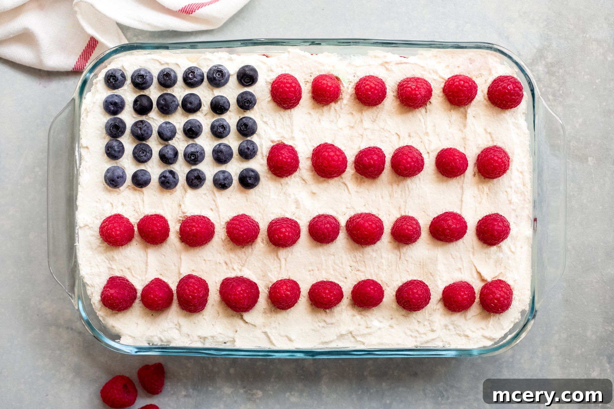 The finished no-bake American flag cake, showcasing its vibrant red, white, and blue design created with fresh berries and creamy layers in a glass dish.