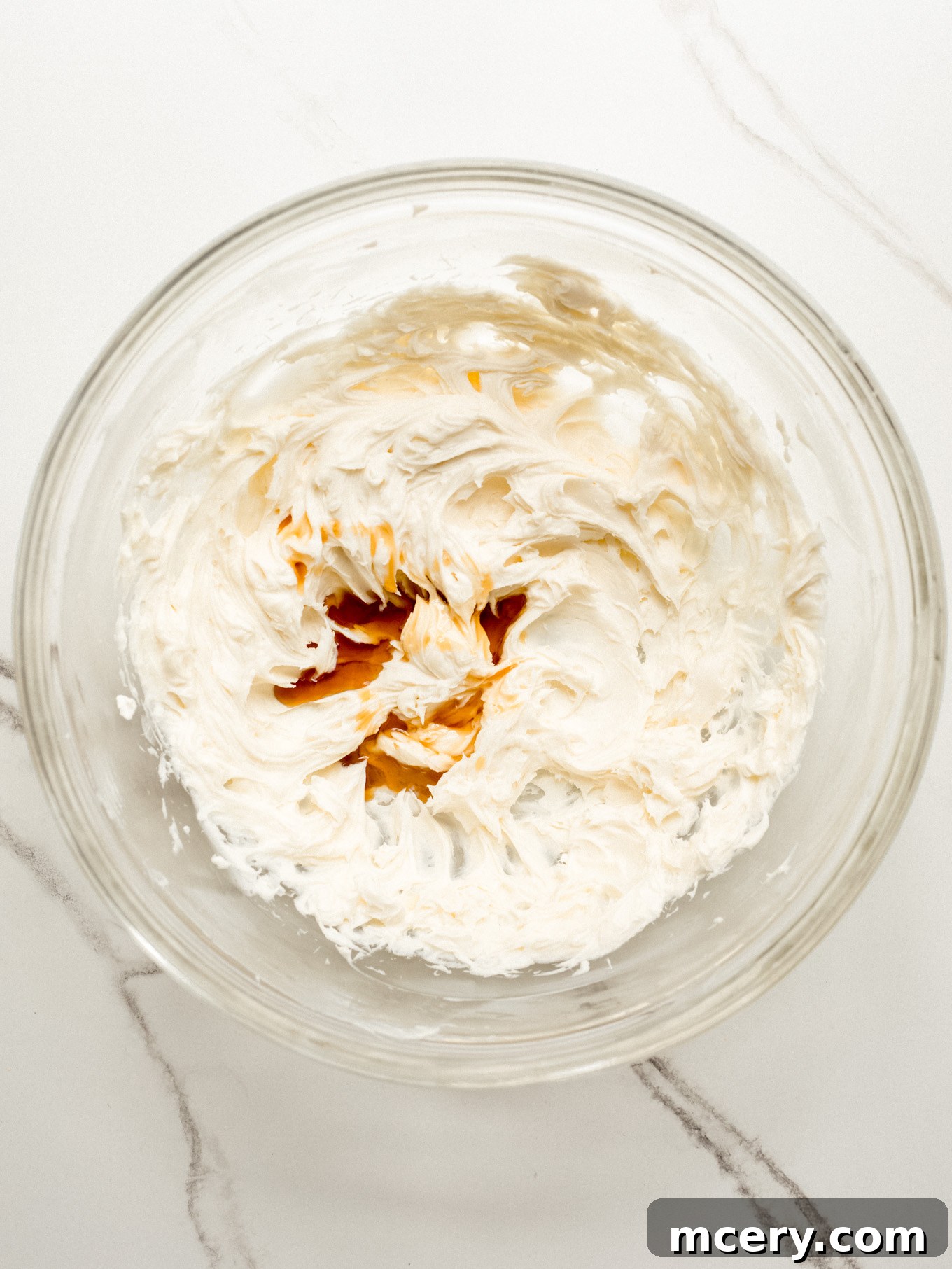 The smooth cream cheese mixture after adding vanilla extract, highlighting the rich, creamy texture ready for the next step.
