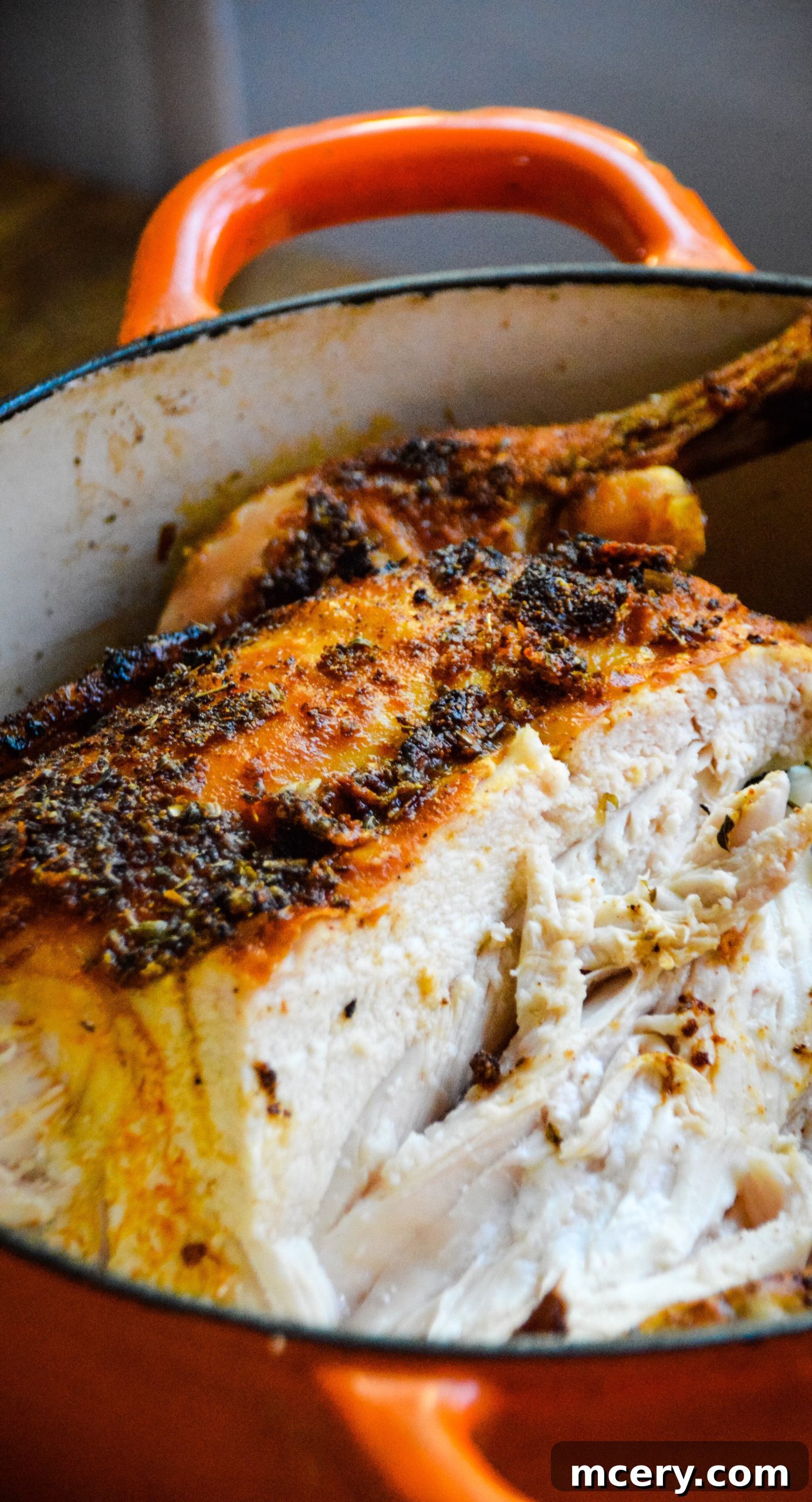Close-up of a carved slice of roasted chicken, showing its juicy texture, next to roasted vegetables.