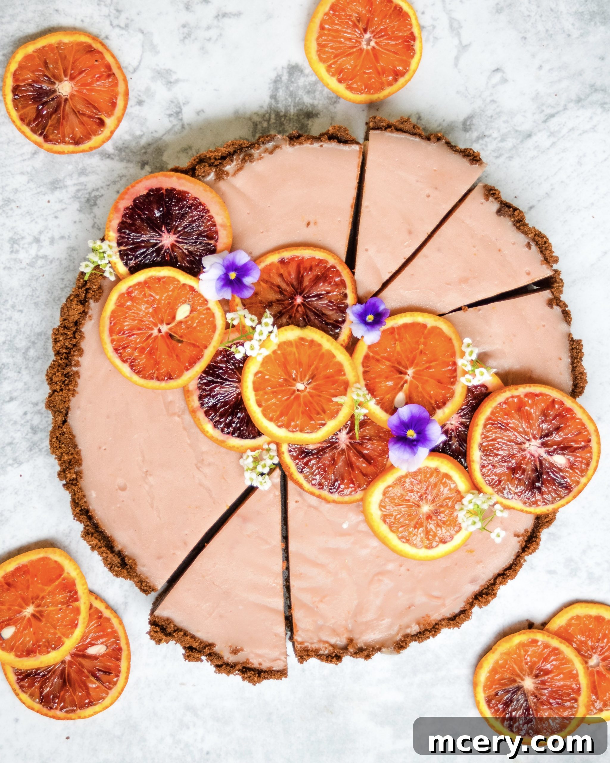 Zesty Blood Orange Tart 2 A beautifully presented, perfectly sliced blood orange tart revealing its vibrant orange filling and dark chocolate crust, garnished with fresh blood orange segments.