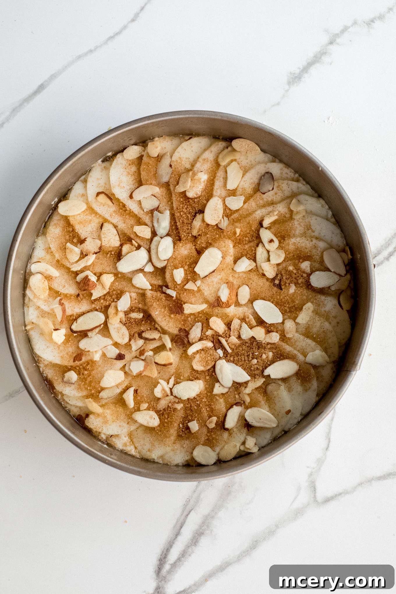 Golden Pear Cake 11 The pear cake batter in a springform pan, generously topped with the almond, cinnamon, and turbinado sugar mixture.