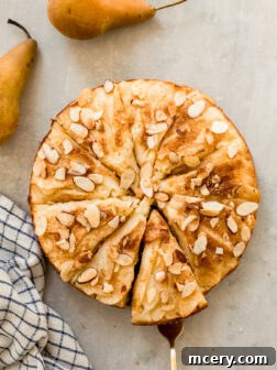 Sliced pear cake with fresh pears arranged alongside for a charming presentation.