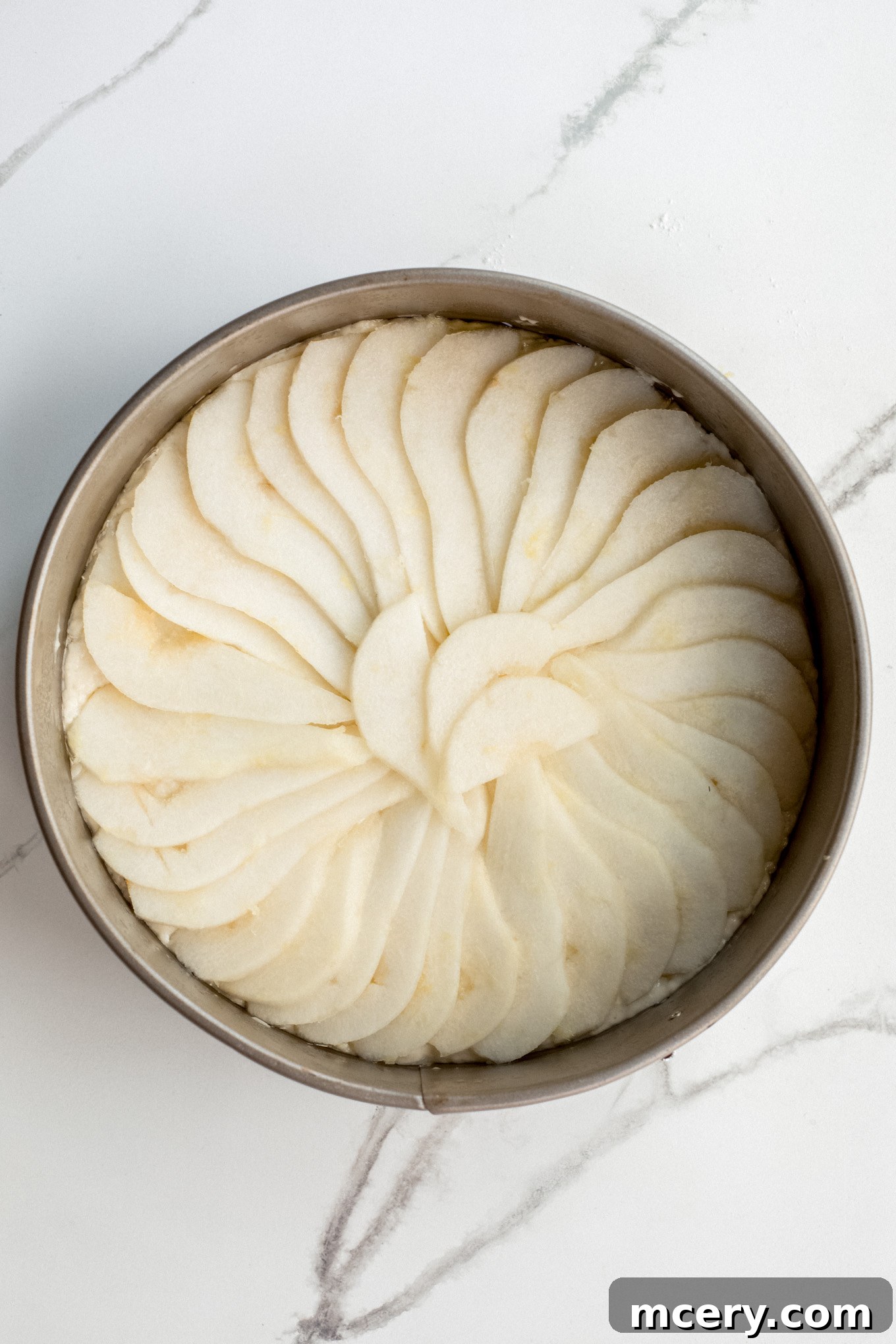 Golden Pear Cake 9 Finely sliced pears layered artfully over the cake batter in an overlapping pattern within the springform pan.