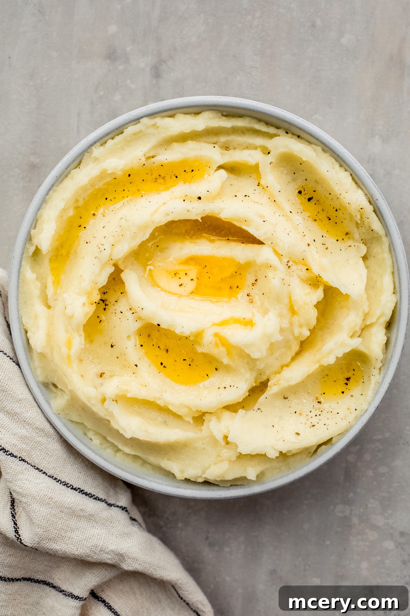 Silky Yukon Gold Mash 2 Yukon Gold mashed potatoes in a bowl with melted butter over the top, ready to be served.