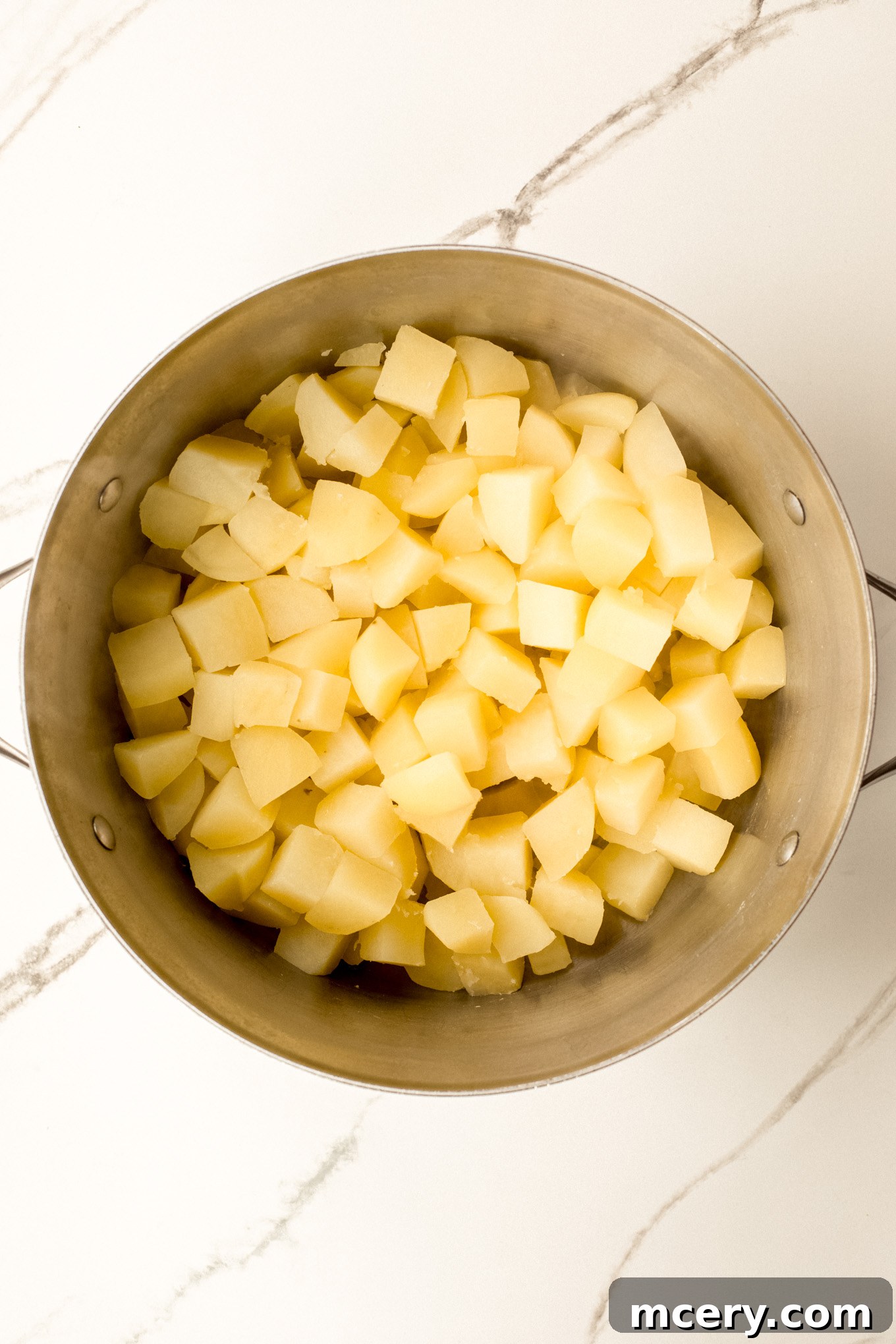 Silky Yukon Gold Mash 5 Cooked and thoroughly drained potatoes in a stockpot, ready for mashing.