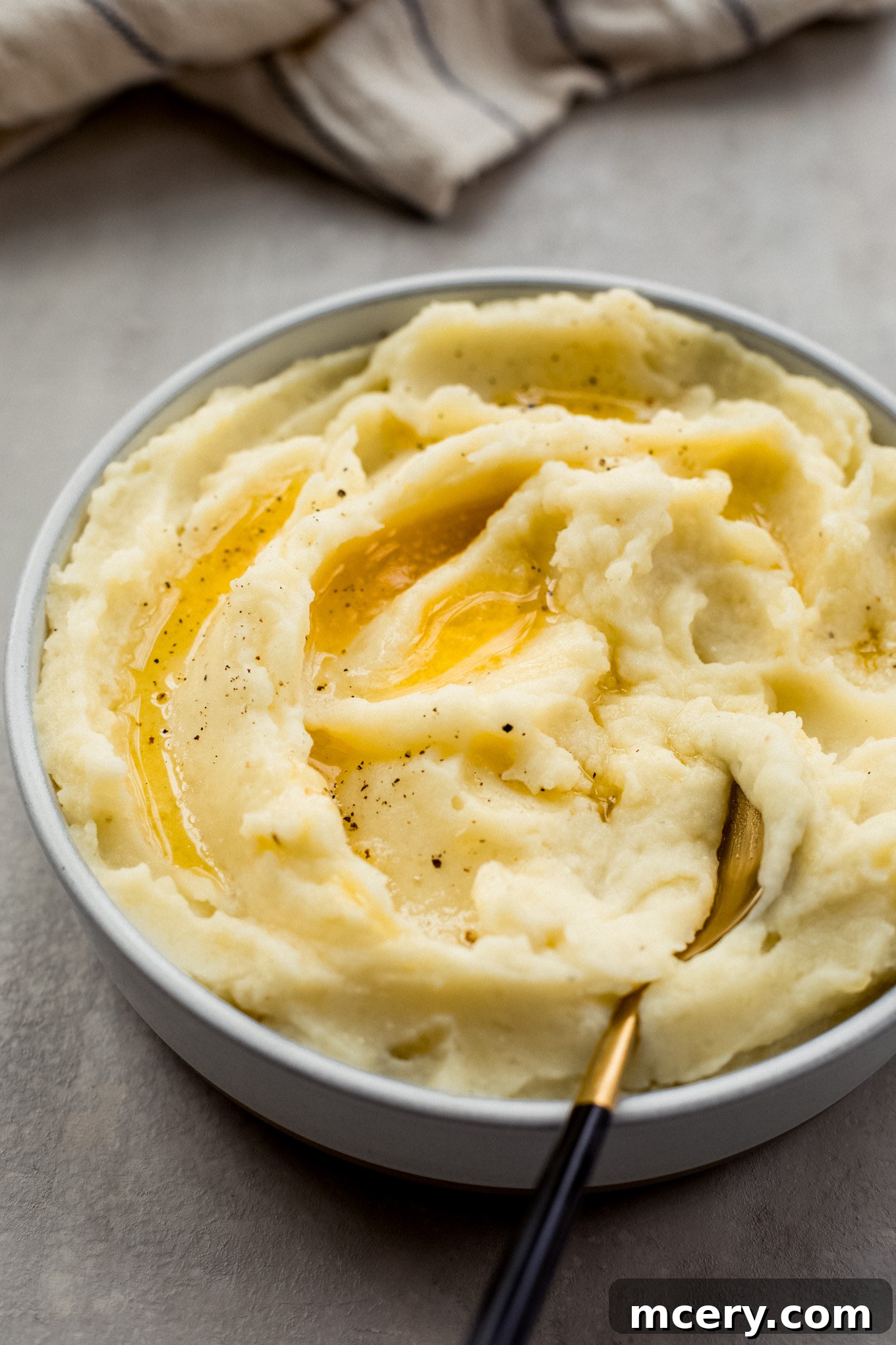 Silky Yukon Gold Mash 10 Close-up of creamy Yukon Gold mashed potatoes in a bowl, with a spoon on the side, highlighting their smooth texture.