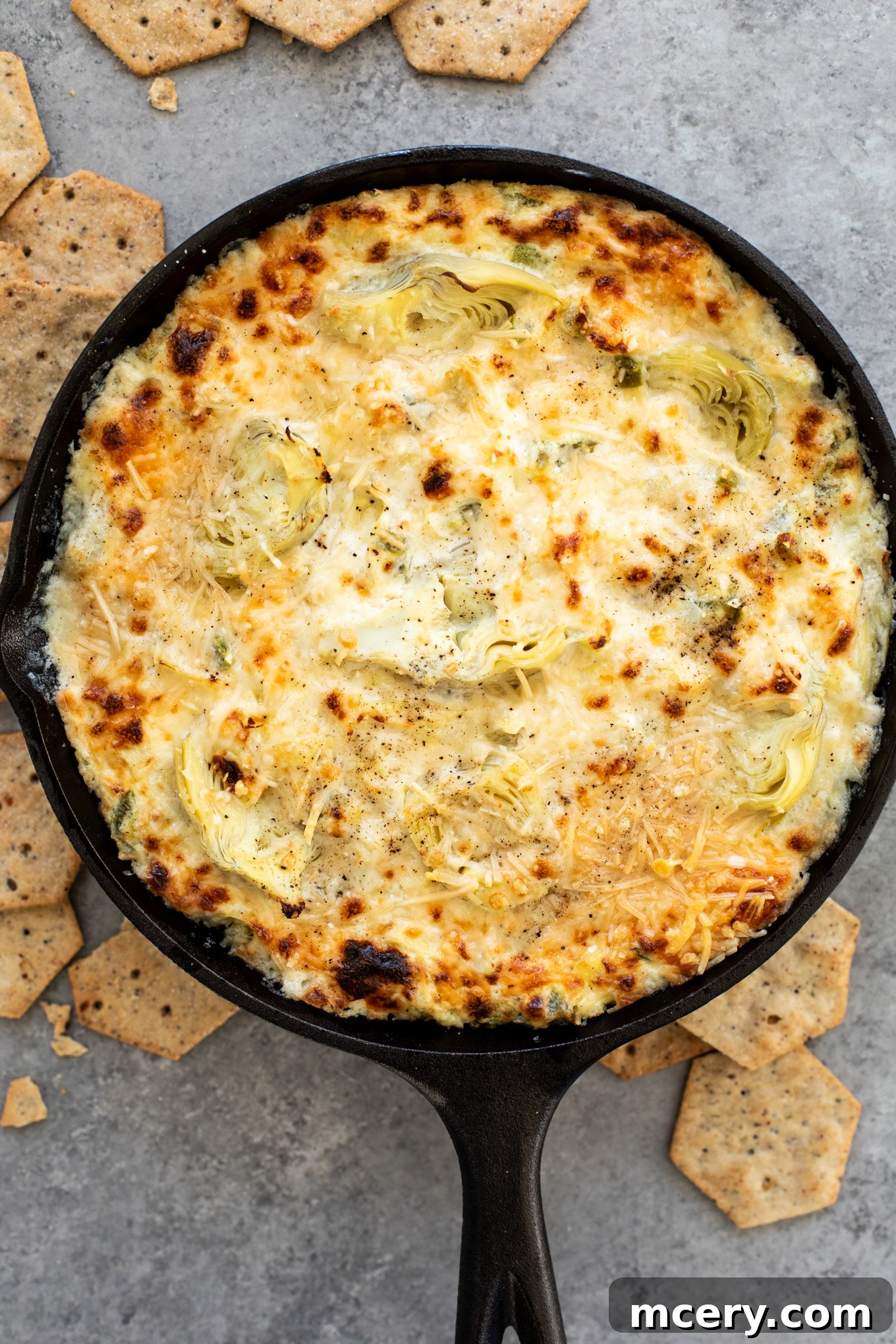 Spicy Jalapeno Artichoke Dip 2 A bubbling baked jalapeno artichoke dip in a rustic cast iron skillet, ready to be served.