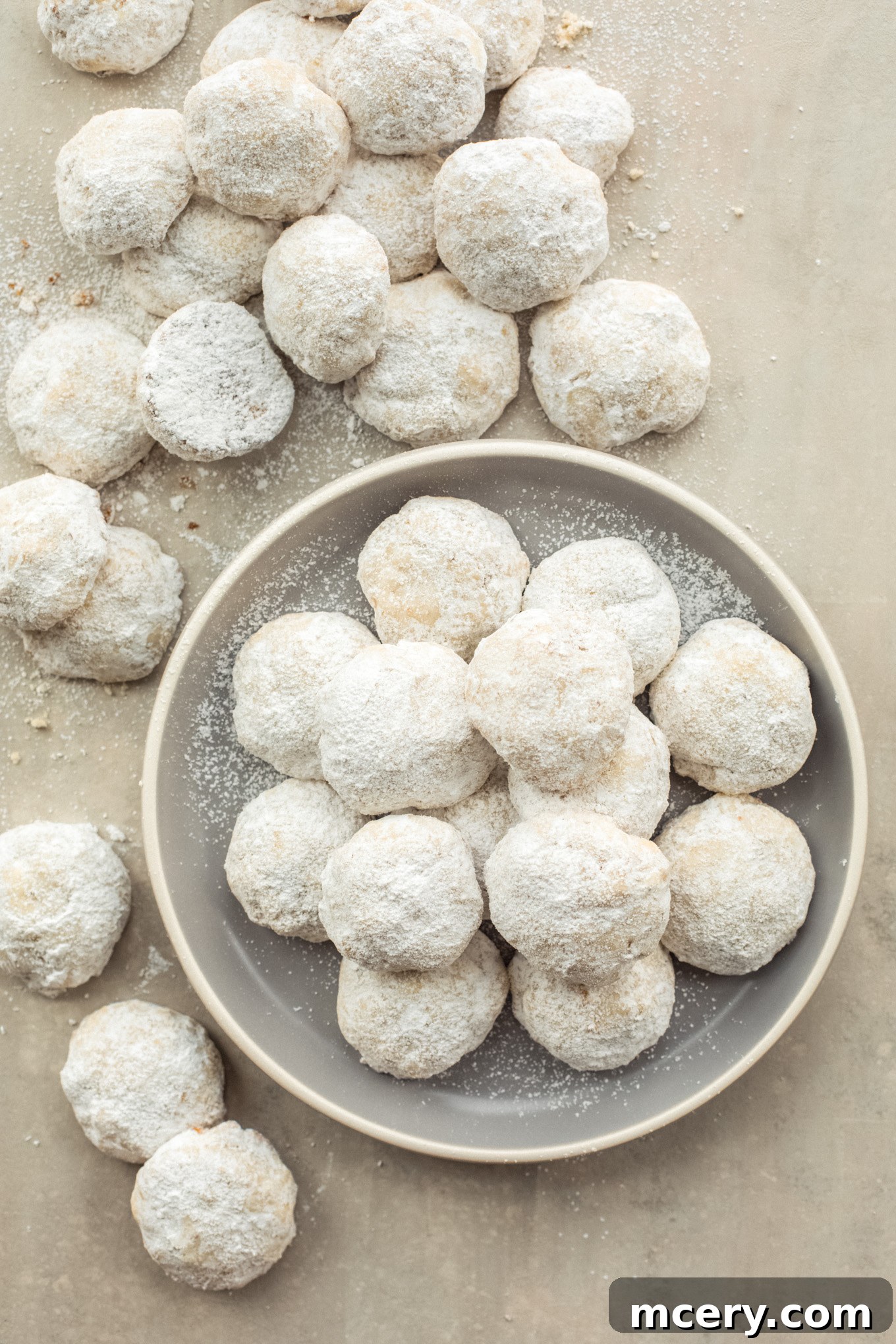Buttery Pecan Snowflakes 2 A plate piled high with fluffy, sugar-dusted pecan ball cookies, ready to be enjoyed during the festive season.