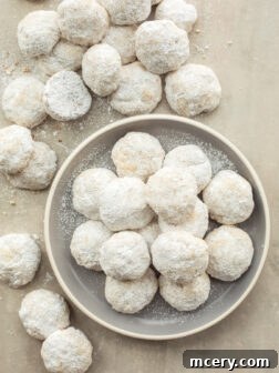 Buttery Pecan Snowflakes 11 Pecan ball cookies served on a decorative plate, beautifully coated in confectioners' sugar.
