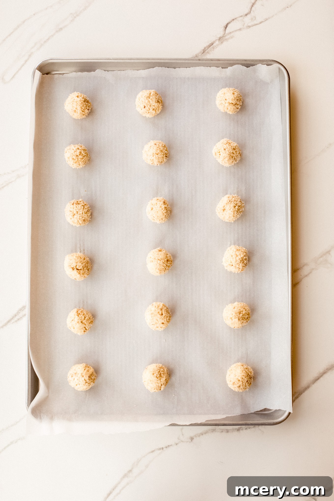 Buttery Pecan Snowflakes 8 Small, perfectly rolled cookie dough balls neatly arranged on a parchment-lined baking sheet, spaced apart for even baking.