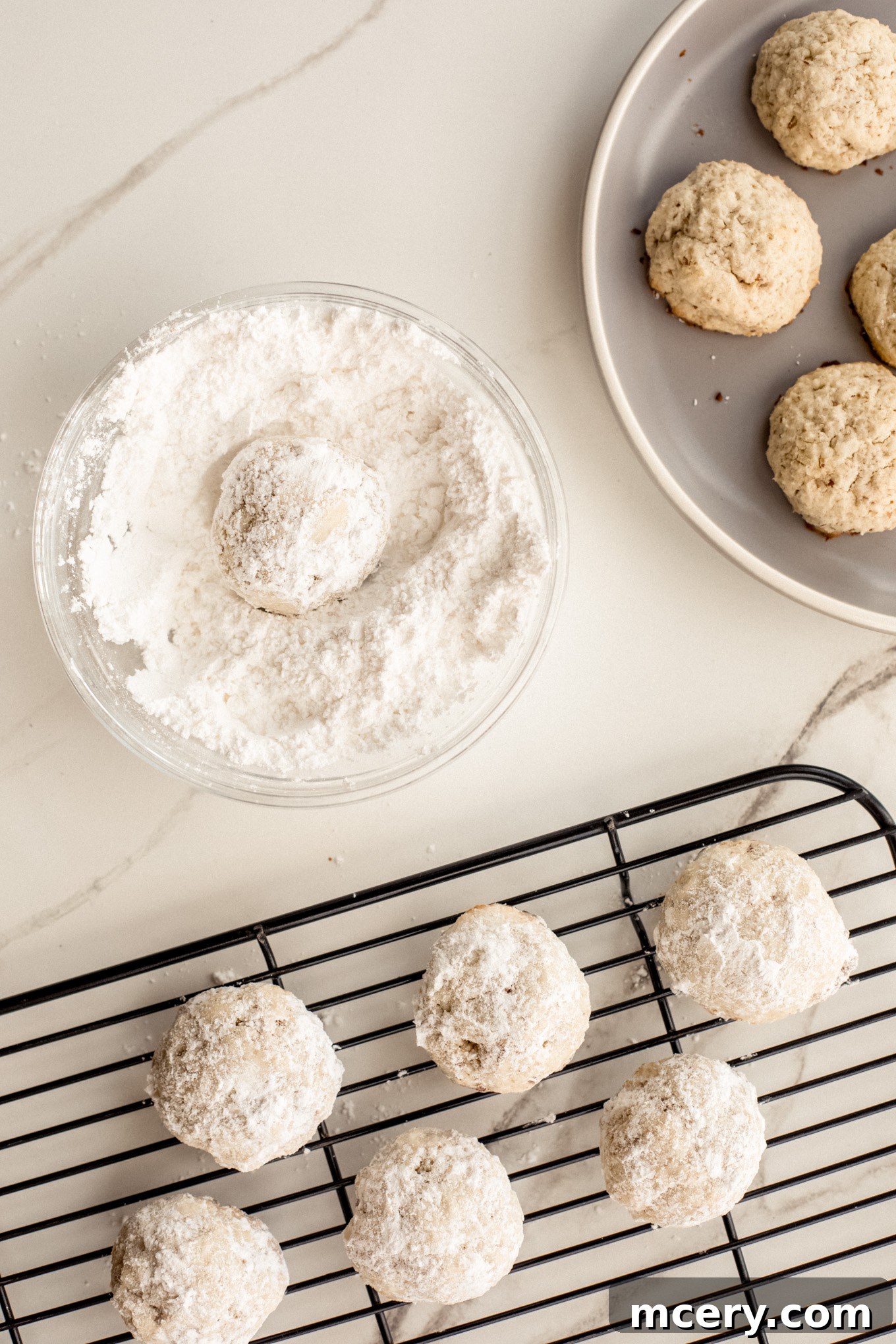 Buttery Pecan Snowflakes 9 Freshly baked cookies are being rolled in a generous bowl of confectioners' sugar, creating their signature snowy coating.