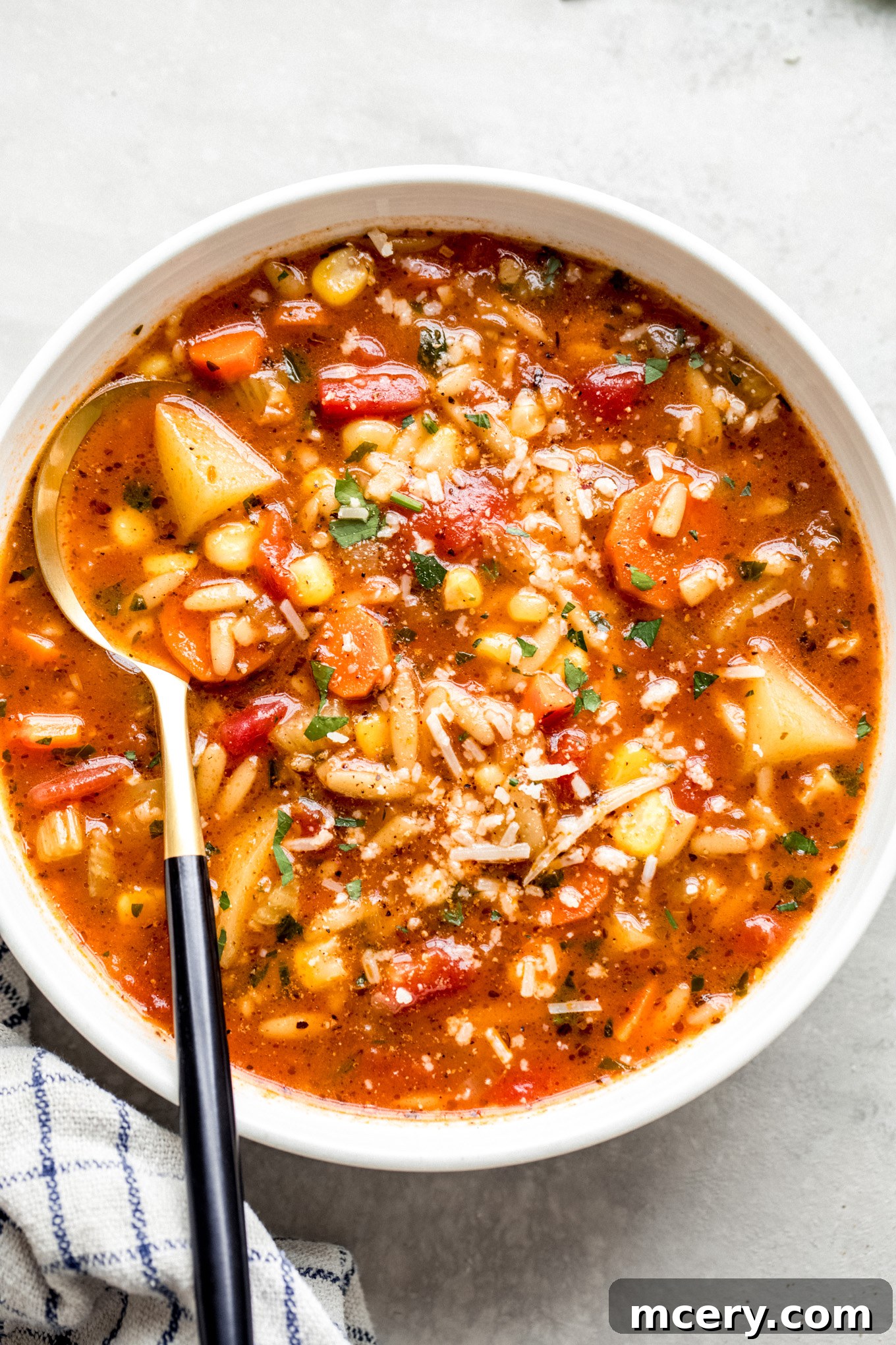 Hearty Garden Orzo Soup 2 white bowl with vegetable soup and a side of a spoon.