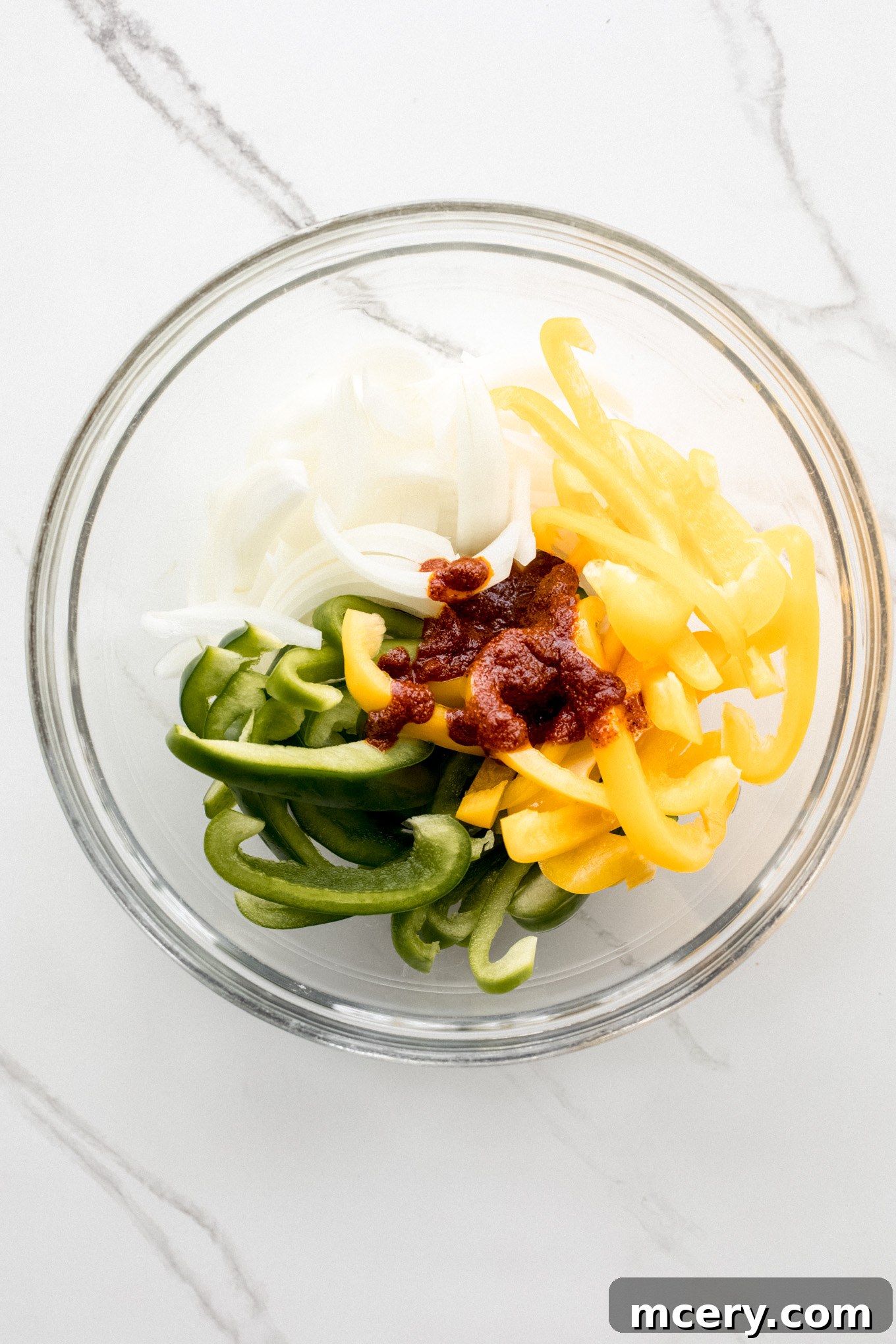 Creamy Chicken Fajita Pasta 6 cut up peppers and onions in a glass bowl topped with spice mixture.