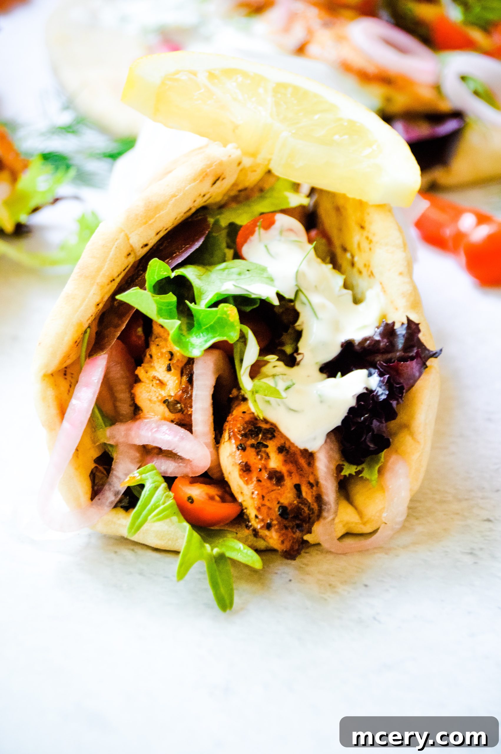 Plated Greek Chicken Gyro, showcasing marinated chicken, fresh vegetables, and creamy tzatziki sauce in a warm pita.