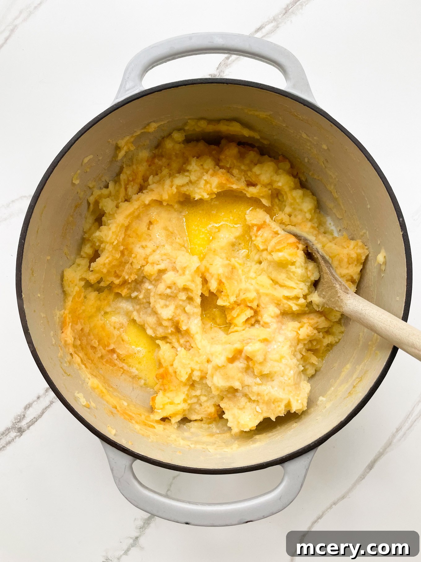 The mashed potatoes in a pot, now fully creamed and smooth after the second addition of the milk mixture, indicating a perfect consistency.